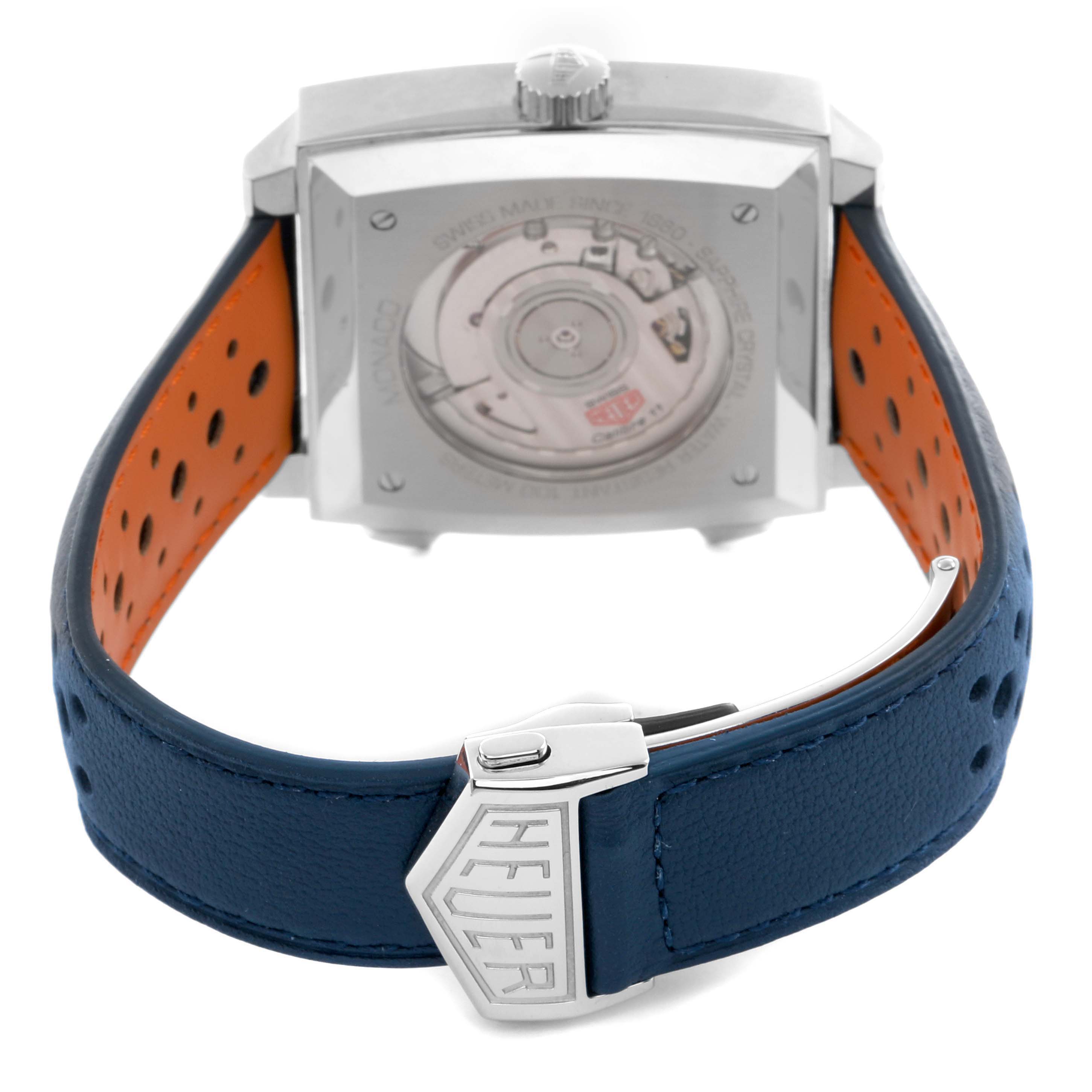 The Tag Heuer Monaco CAW211R Men
s Stainless Steel Blue Dial watch is shown from the back, highlighting its movement and blue strap with a "Heuer" clasp.