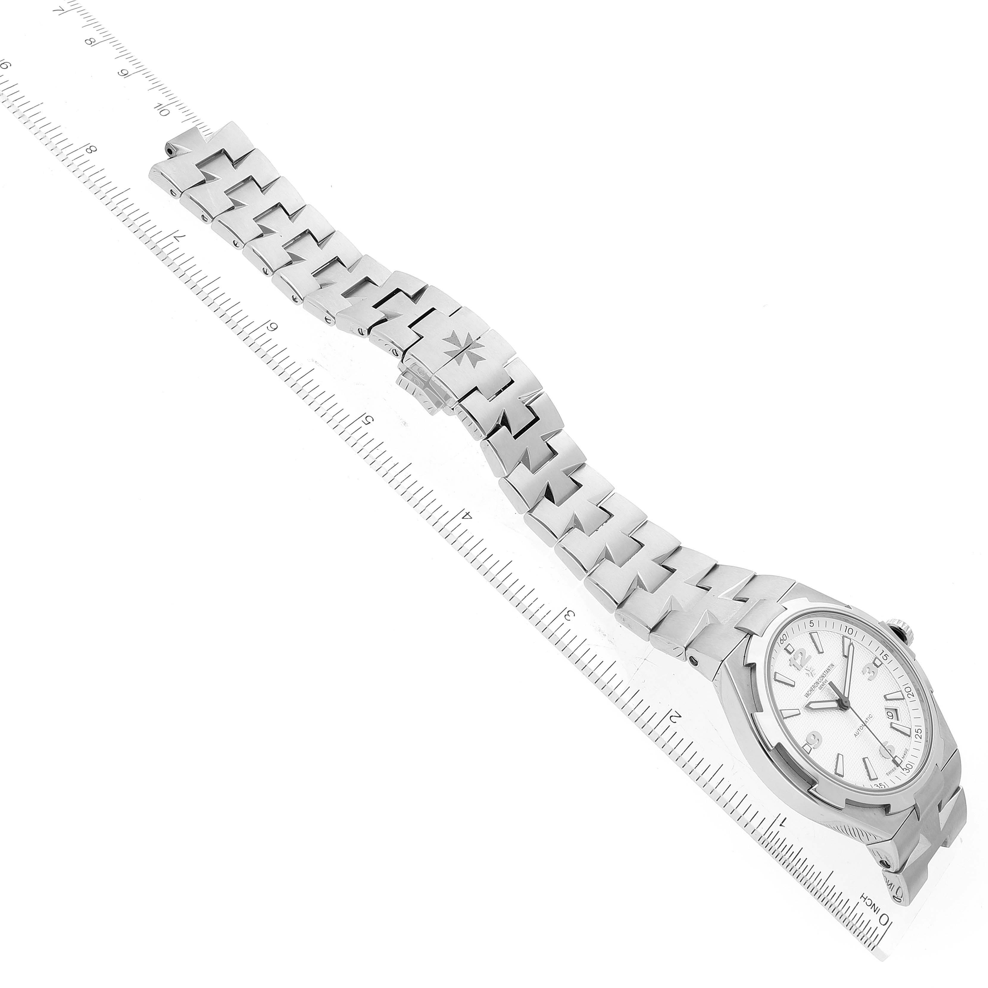 The image shows a Vacheron Constantin Overseas 47040B01A-9093 Men
s Stainless Steel Silver Dial 47040B01A-9093 Men
s Stainless Steel Silver Dial watch lying flat with its face, bracelet, and clasp visible, alongside a ruler.