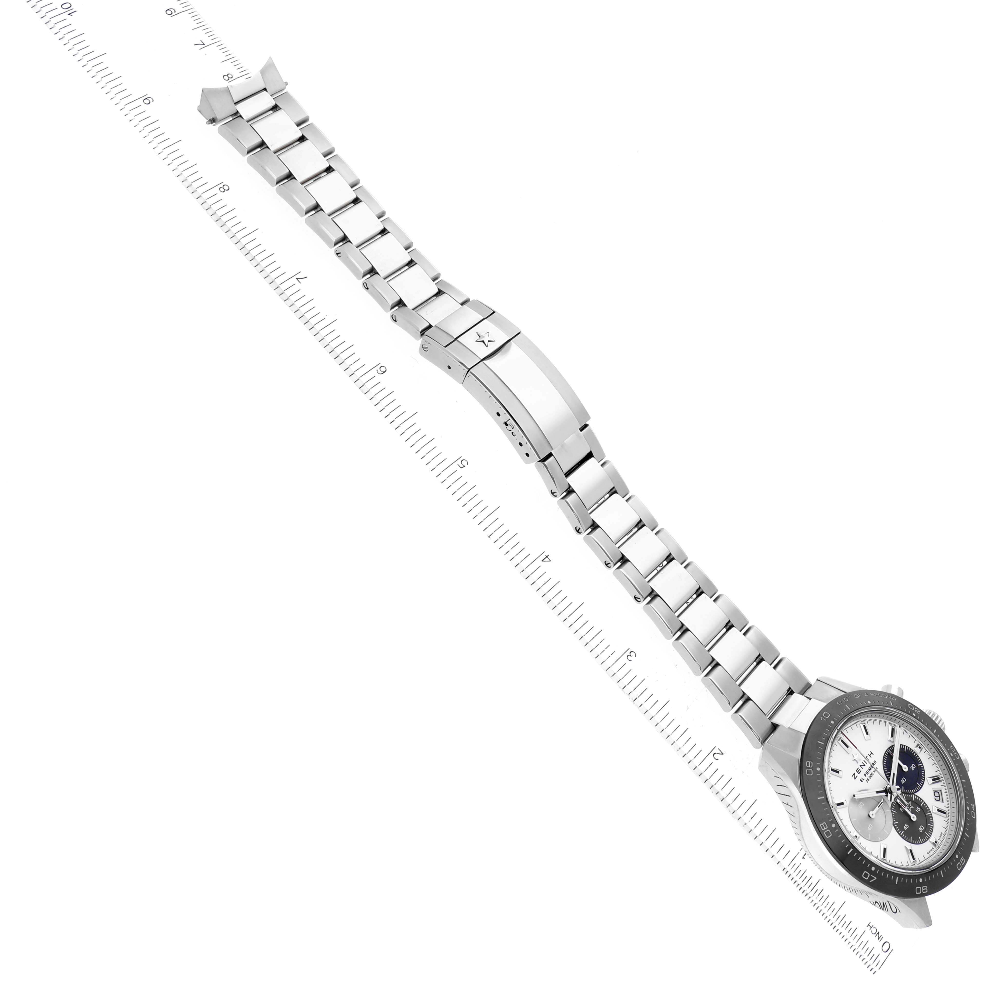 The Zenith Chronomaster 03.3100.3600/69.M3100 Men's Stainless Steel White Dial 03.3100.3600/69.M3100 Men's Stainless Steel White Dial watch is shown at an angle showcasing the face, bezel, bracelet, and clasp alongside a measuring scale.