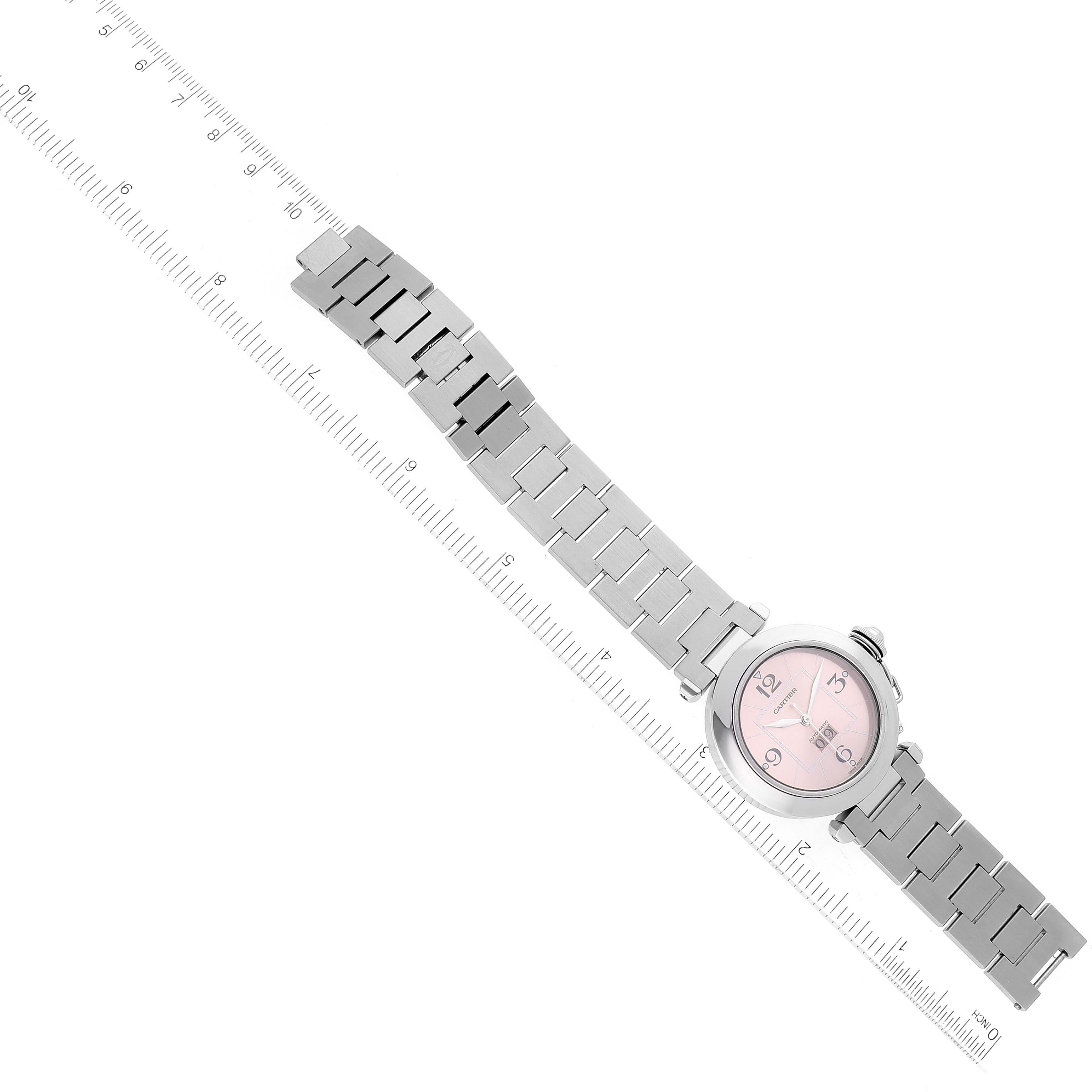 The Cartier Pasha W31058M7 Women's Stainless Steel Pink Dial W31058M7 Women's Stainless Steel Pink Dial watch is shown at a slight diagonal angle, displaying its metal bracelet and round face with a ruler underneath.