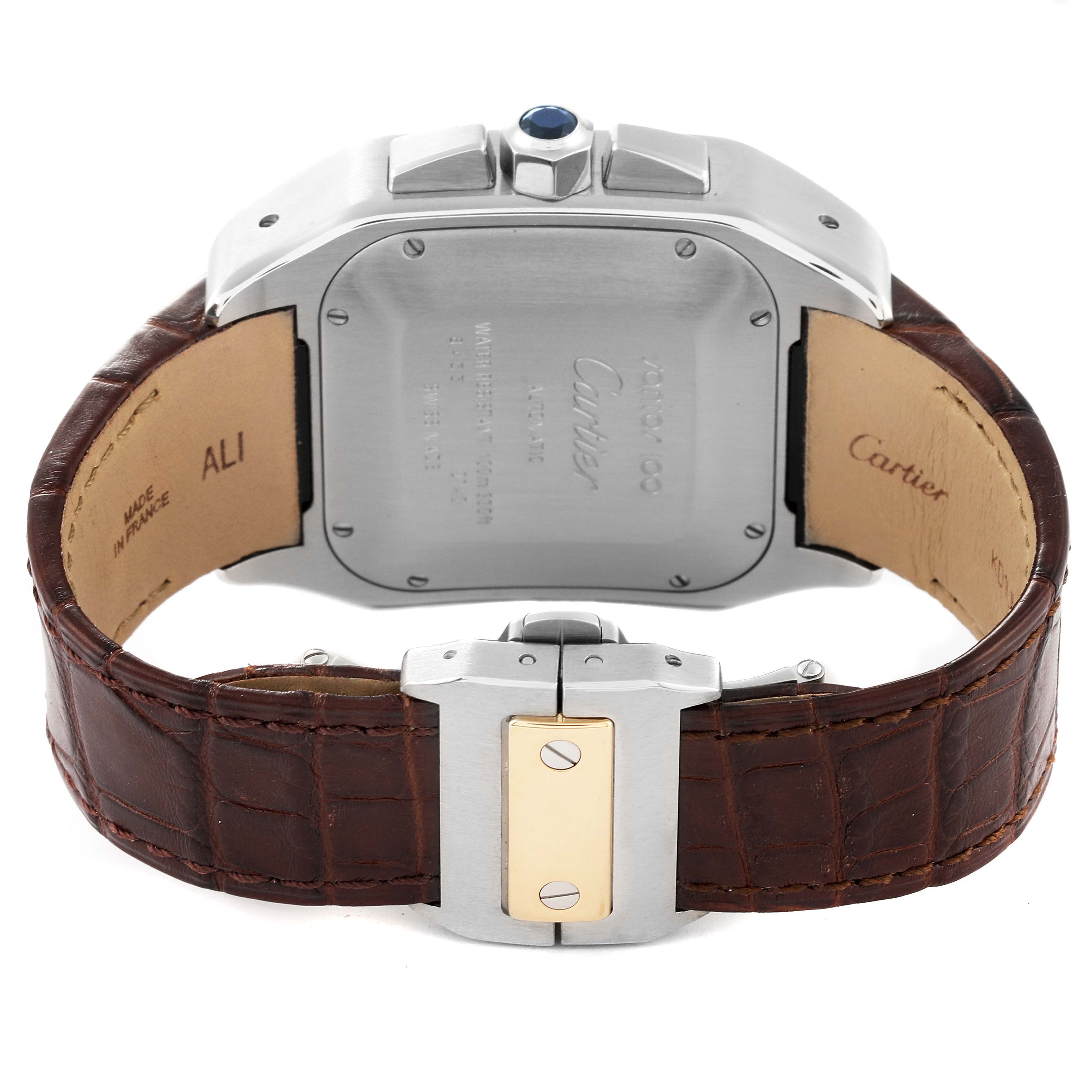The image shows the back of the Cartier Santos W20091X7 Men's Steel and Gold (two tone) Silver Dial W20091X7 Men's Steel and Gold (two tone) Silver Dial watch, highlighting the case, crown with blue cabochon, and brown leather strap.