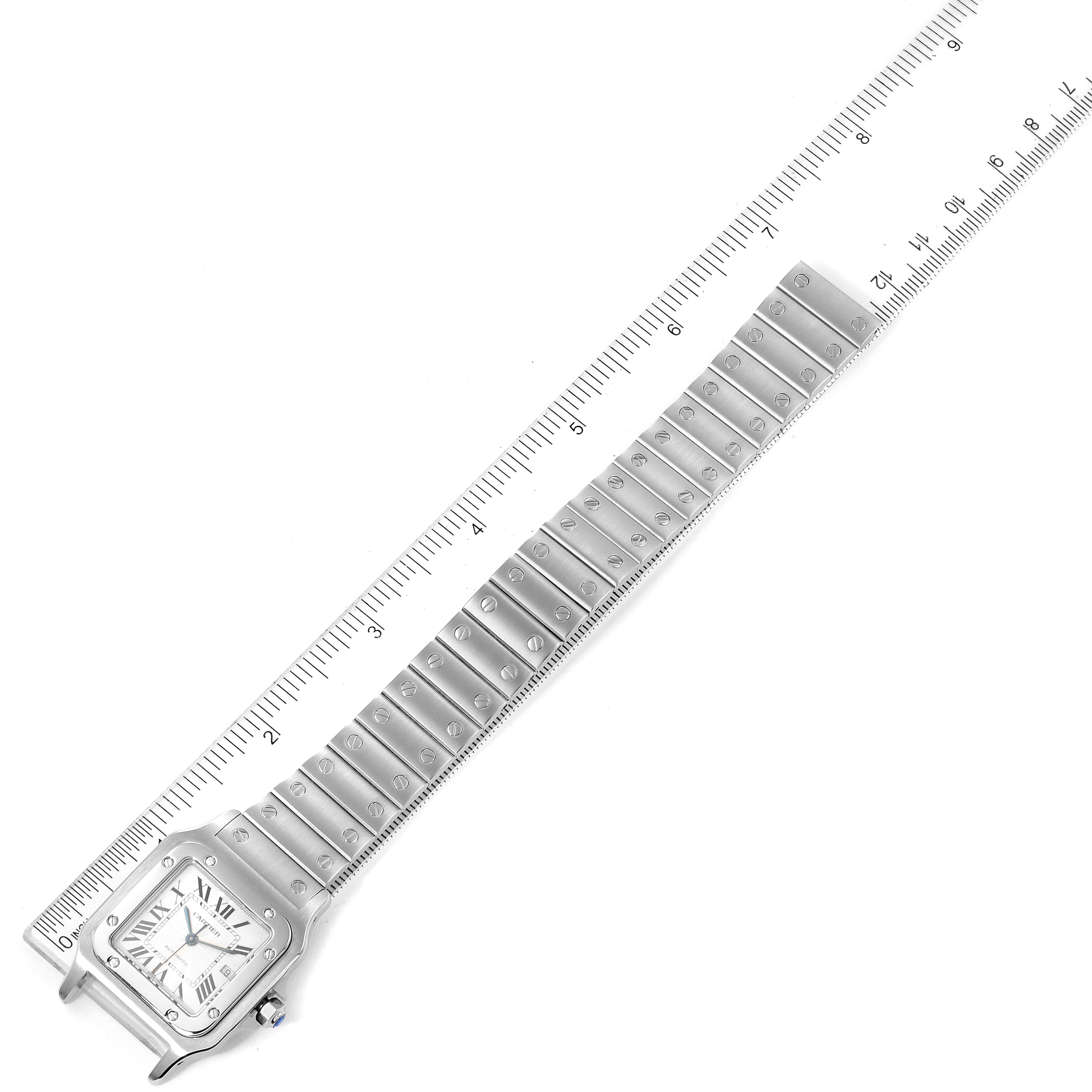 This image shows a Santos model watch by Cartier laid flat, highlighting both the face and the full length of the metal bracelet beside a ruler.