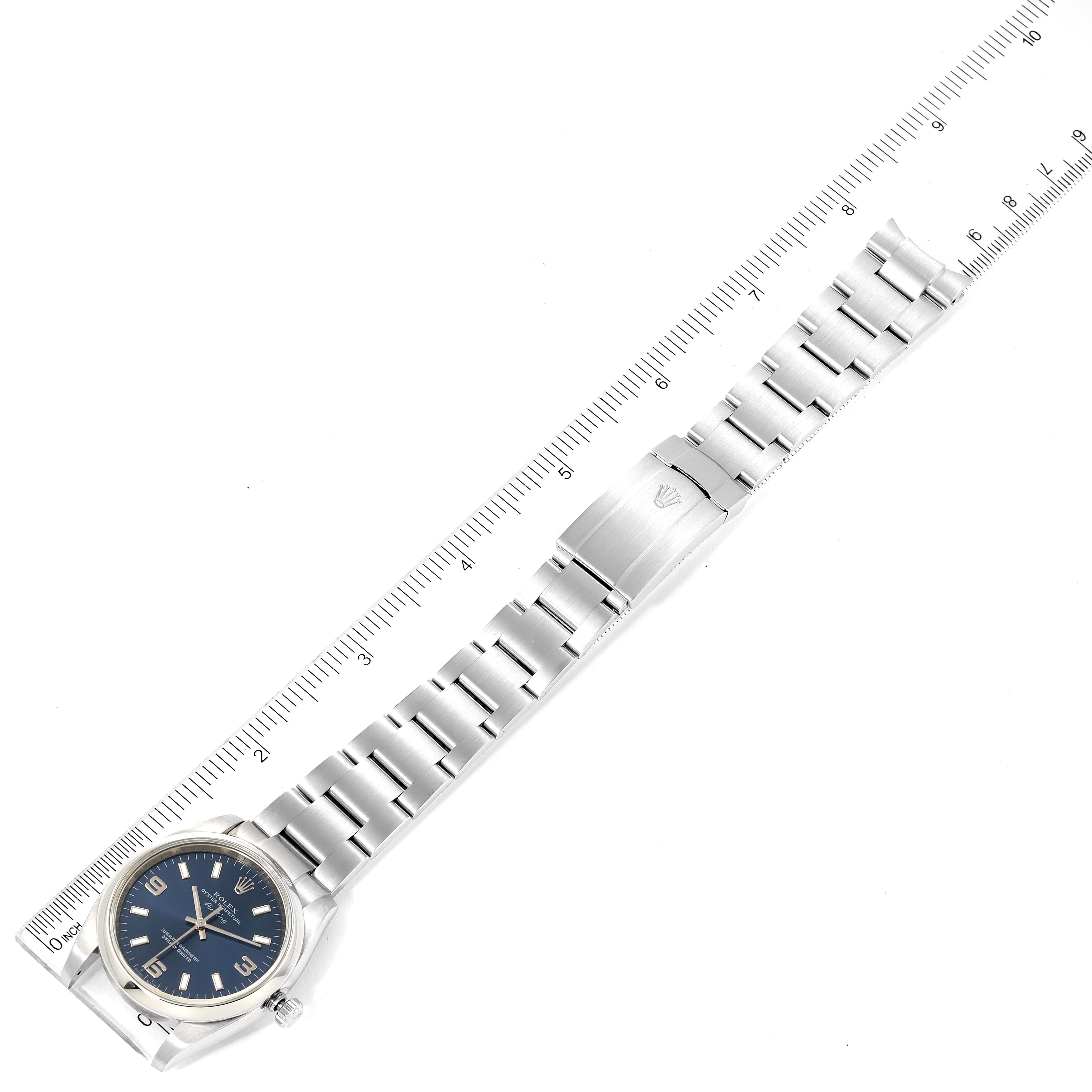 The image shows a top-down view of the Rolex Air-King 114200 Men's Stainless Steel Blue Dial 114200 Men's Stainless Steel Blue Dial watch, displaying its face, bracelet strap, and clasp fully extended next to a ruler.