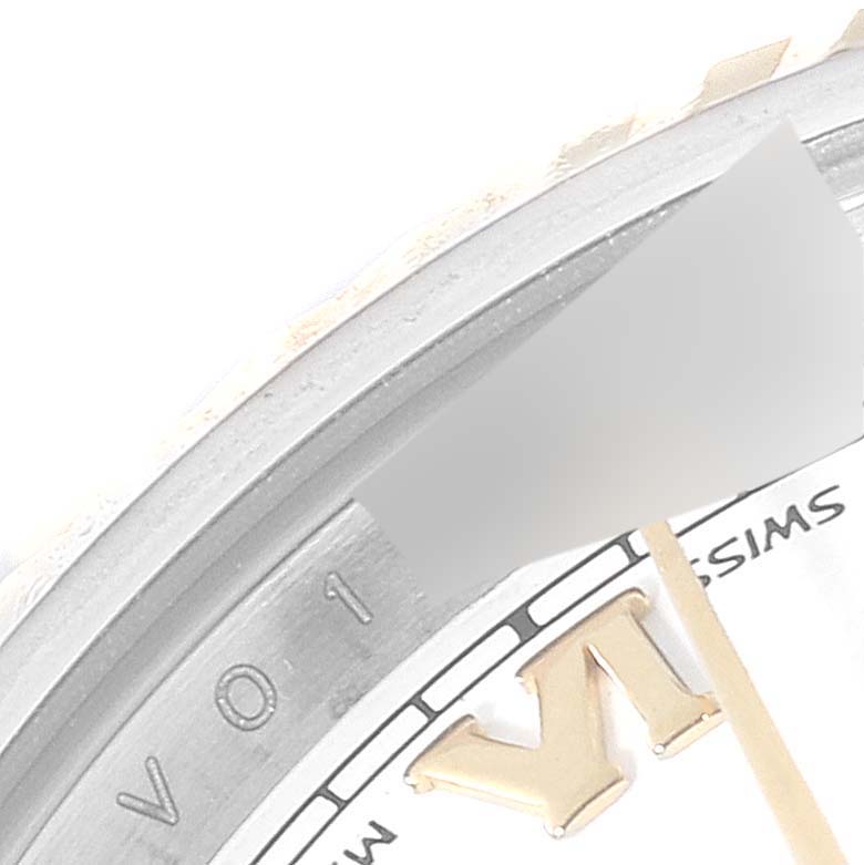 This close-up of a Rolex Datejust 179173 Women's Steel and Gold (two tone) White Dial 179173 Women's Steel and Gold (two tone) White Dial watch shows the bezel, part of the dial, and the letter "V".