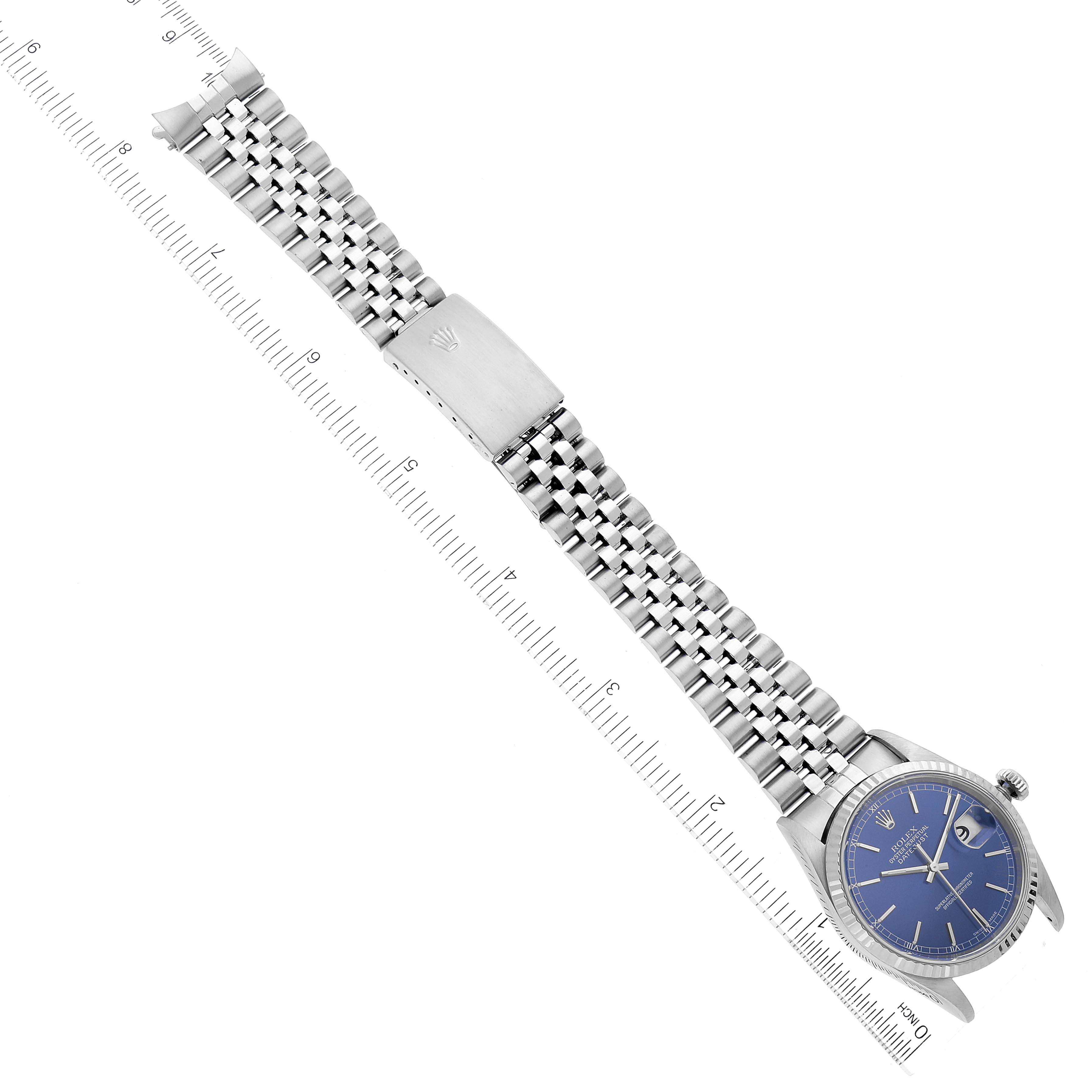 This image shows a Rolex Datejust 16234 Men's Stainless Steel Blue Dial 16234 Men's Stainless Steel Blue Dial watch laid flat with its face, bezel, band, and clasp all visible, alongside measuring scales.