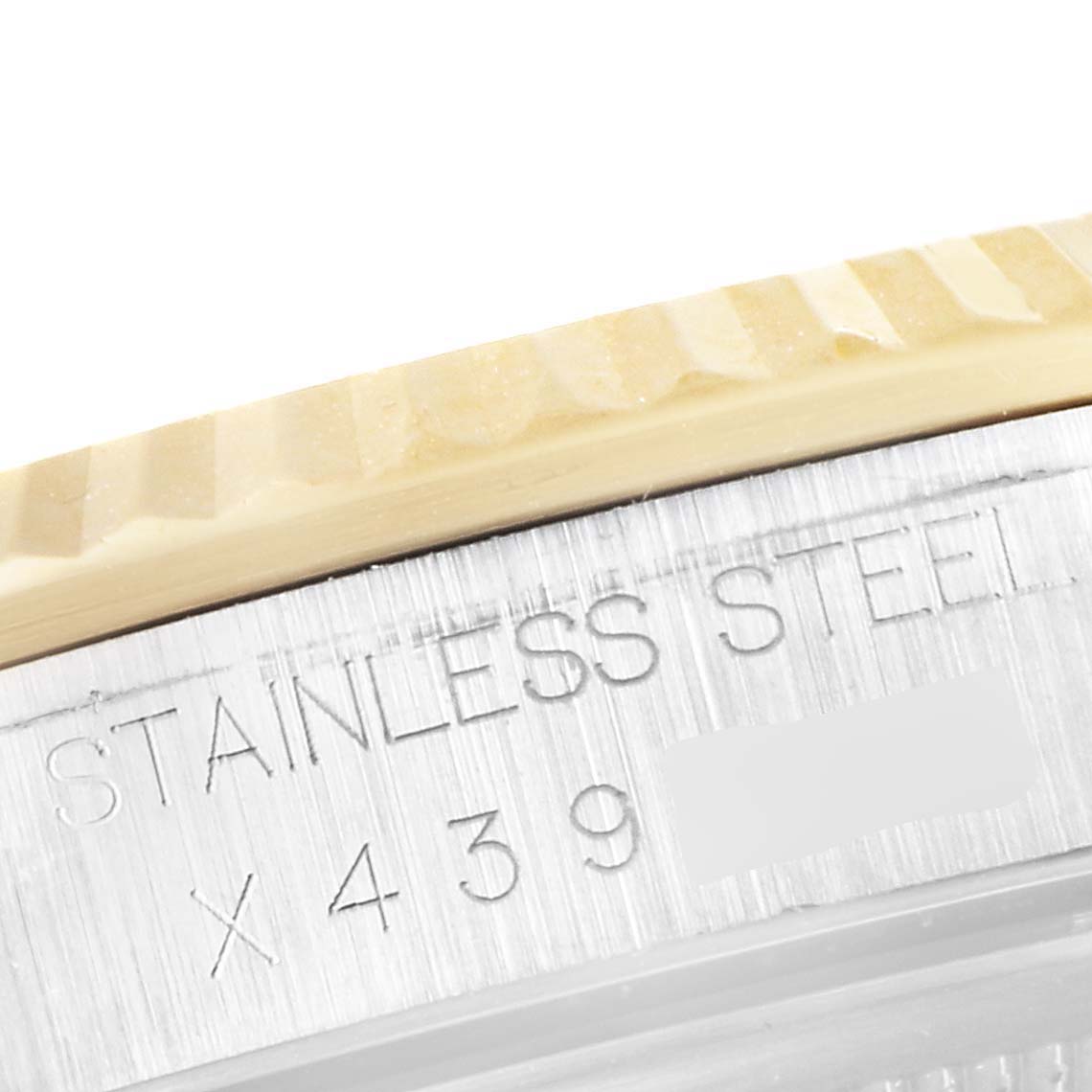 This close-up image of the Rolex Datejust 16233 Men's Steel and Gold (two tone) Champagne Dial 16233 Men's Steel and Gold (two tone) Champagne Dial watch shows part of the fluted bezel and the engraving on the stainless steel case back.