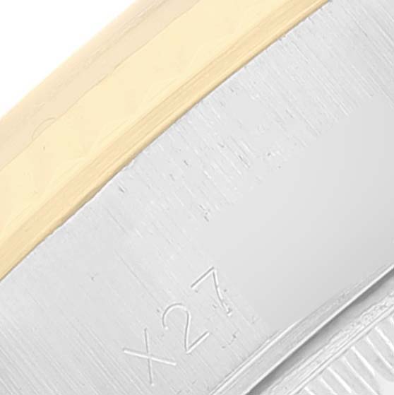 This close-up image of the Rolex Datejust 69173 Women's Steel and Gold (two tone) Champagne Dial 69173 Women's Steel and Gold (two tone) Champagne Dial watch shows part of the bezel and casing, including an engraved serial number "X27".
