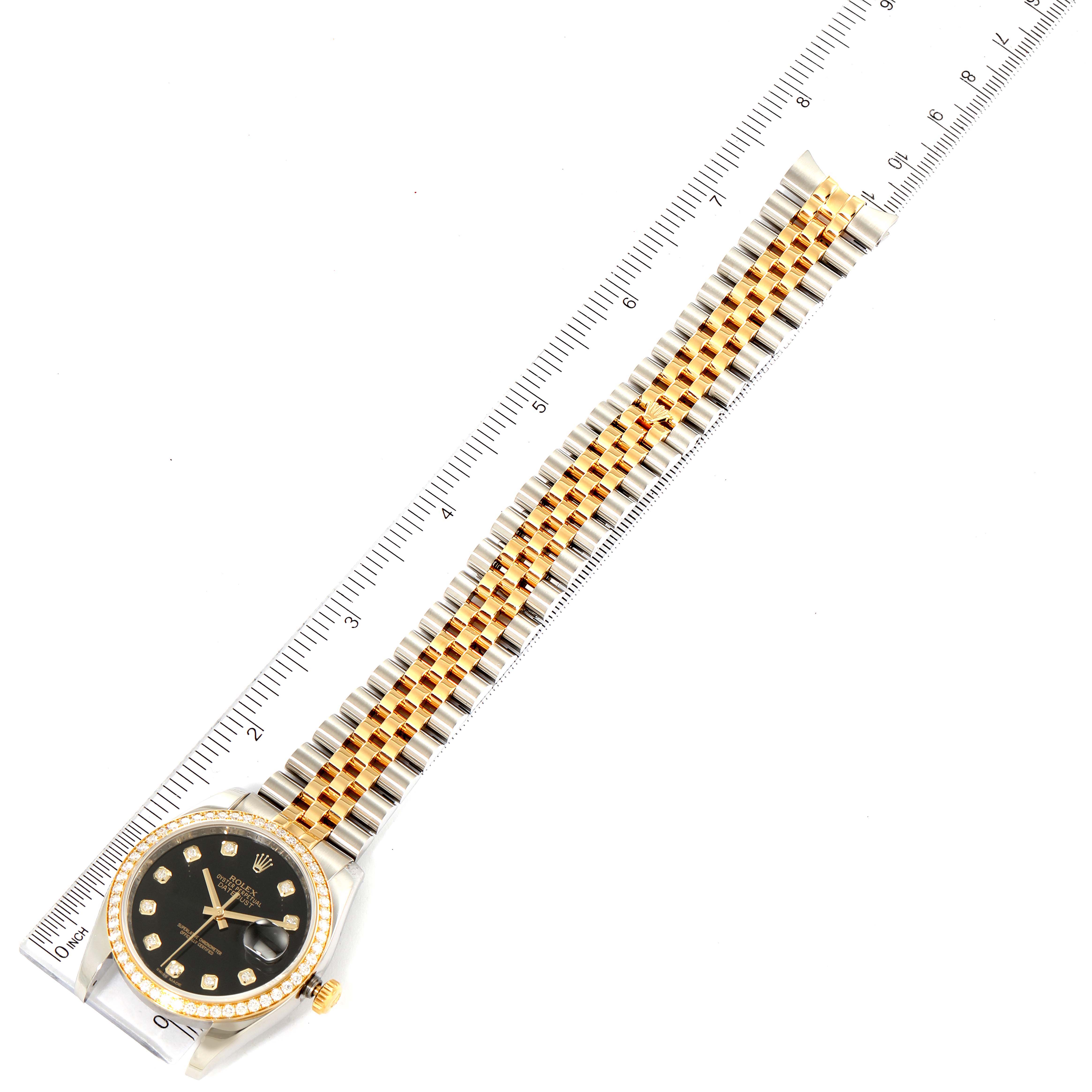 The image shows a top view of the Rolex Datejust 116243 Men's Steel and Gold (two tone) Black Dial 116243 Men's Steel and Gold (two tone) Black Dial watch, focusing on its face and two-tone bracelet next to a ruler.