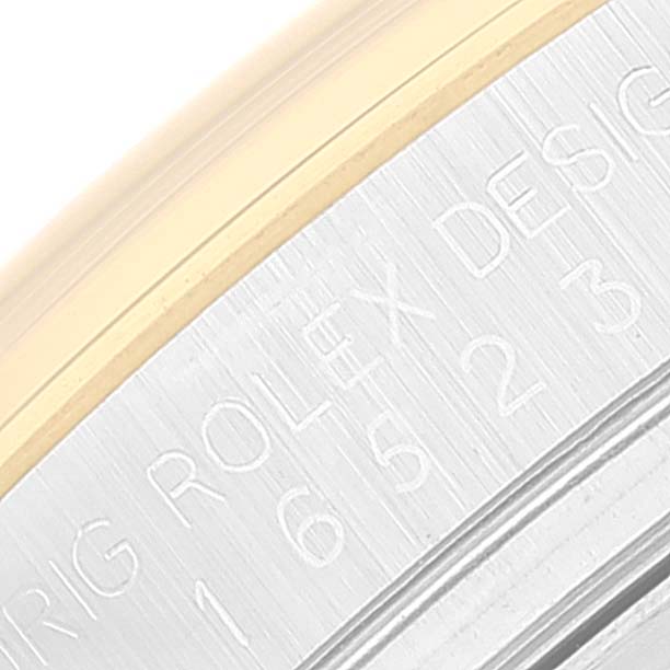 This image shows a close-up of the engraved text on the metal bezel of a Rolex Daytona 16523 Men's Steel and Gold (two tone) Black Dial 16523 Men's Steel and Gold (two tone) Black Dial watch.