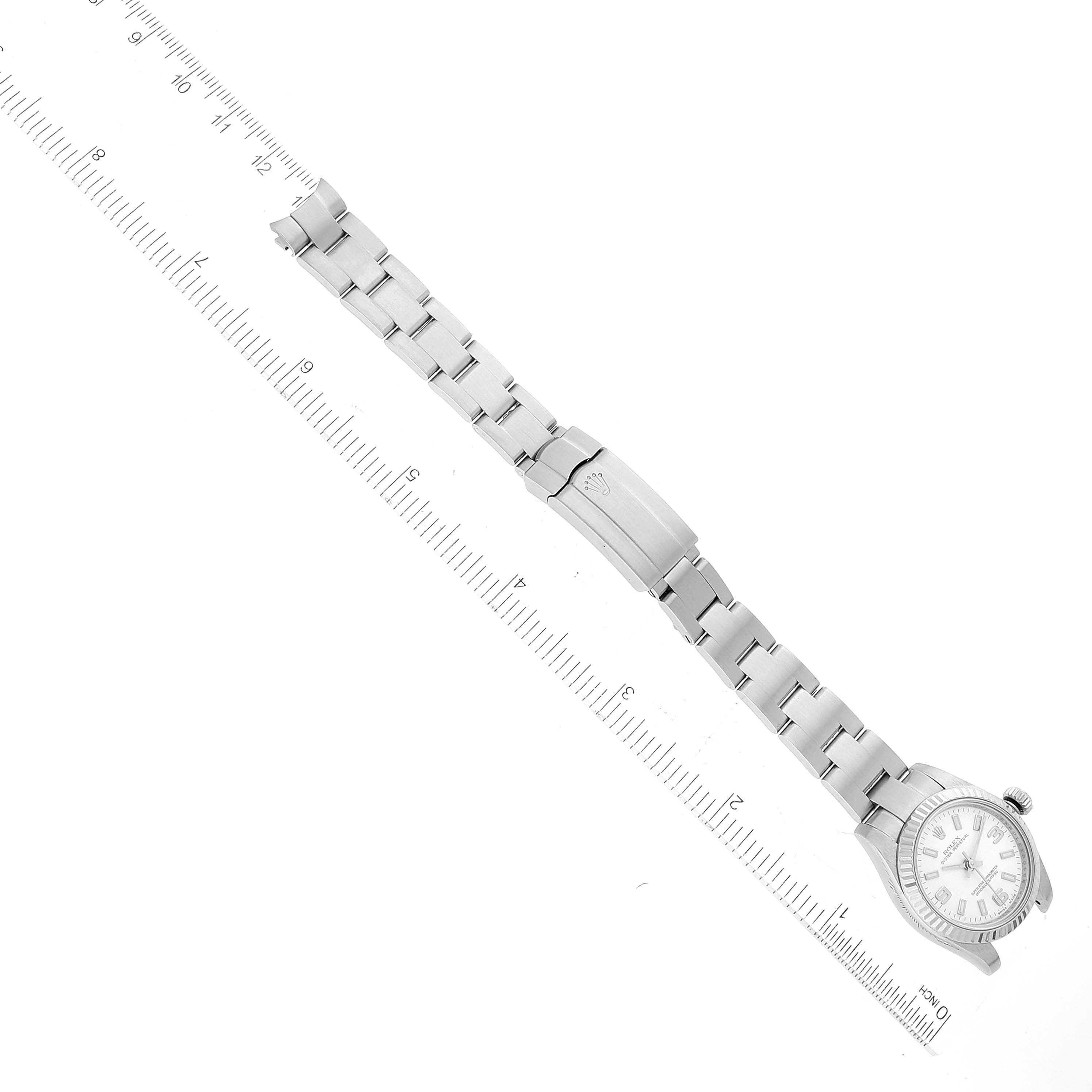 This image shows a Rolex Oyster Perpetual 176234 Women
s Stainless Steel White Dial 176234 Women
s Stainless Steel White Dial watch laid flat with its bracelet extended alongside a measuring ruler.