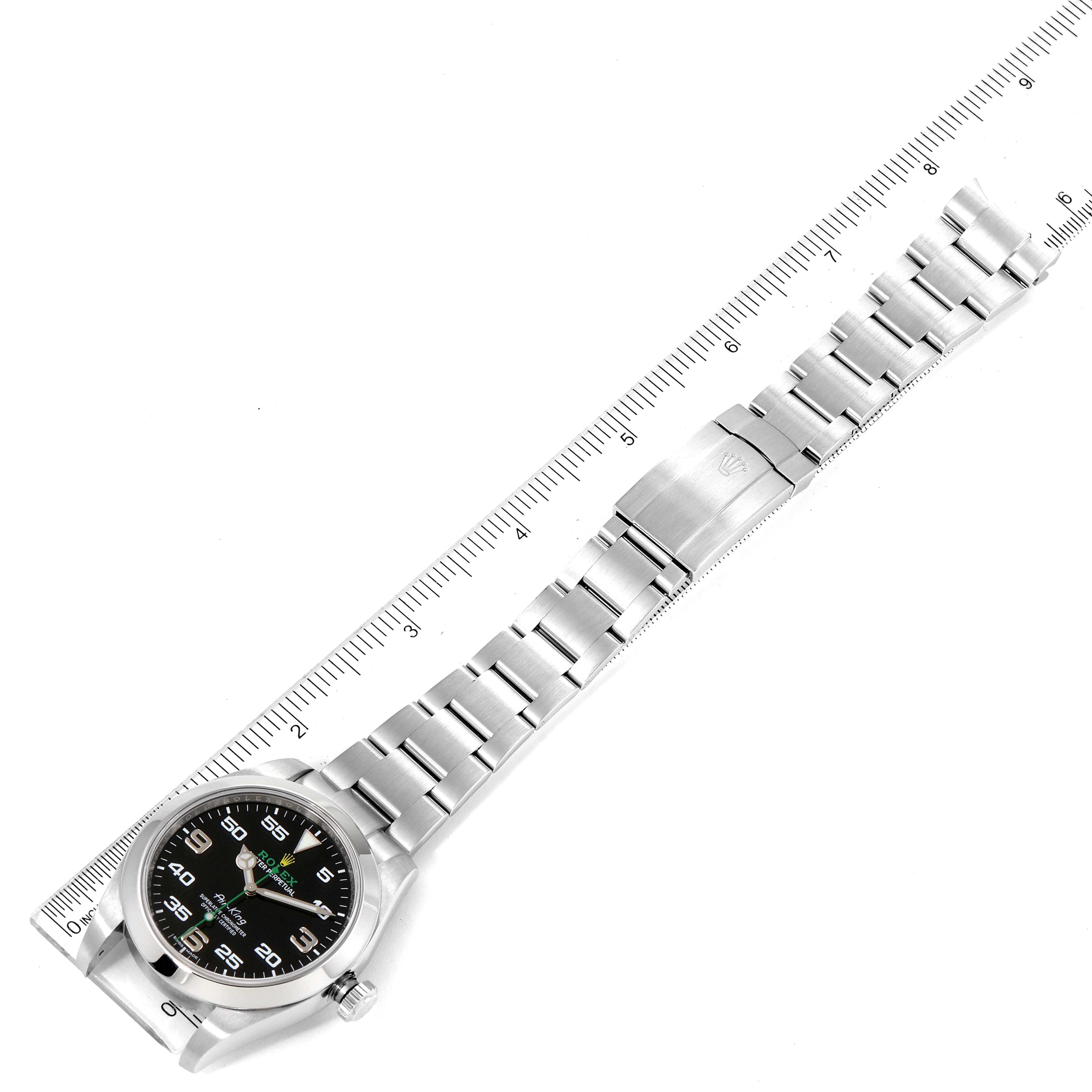 The image shows an overhead view of a Rolex Air-King 116900 Men's Stainless Steel Black Dial 116900 Men's Stainless Steel Black Dial watch with a silver bracelet and ruler for measurement.