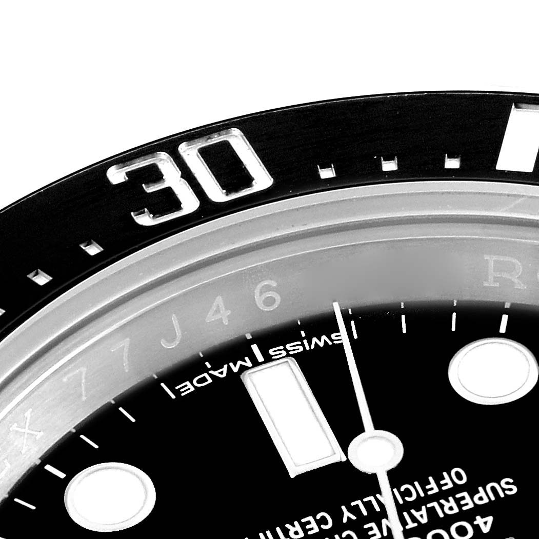 This close-up image of the Rolex Sea-Dweller 126600 Men's Stainless Steel Black Dial 126600 Men's Stainless Steel Black Dial watch shows the bezel, part of the dial, and some hour markers in detail.