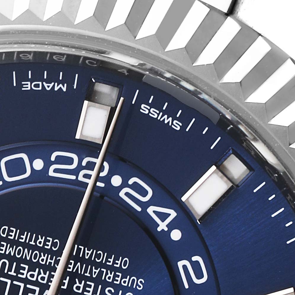 The image shows a close-up of the Rolex Sky-Dweller 326934 Men's Stainless Steel Blue Dial 326934 Men's Stainless Steel Blue Dial watch, focusing on the dial, parts of the hour markers, and the fluted bezel.