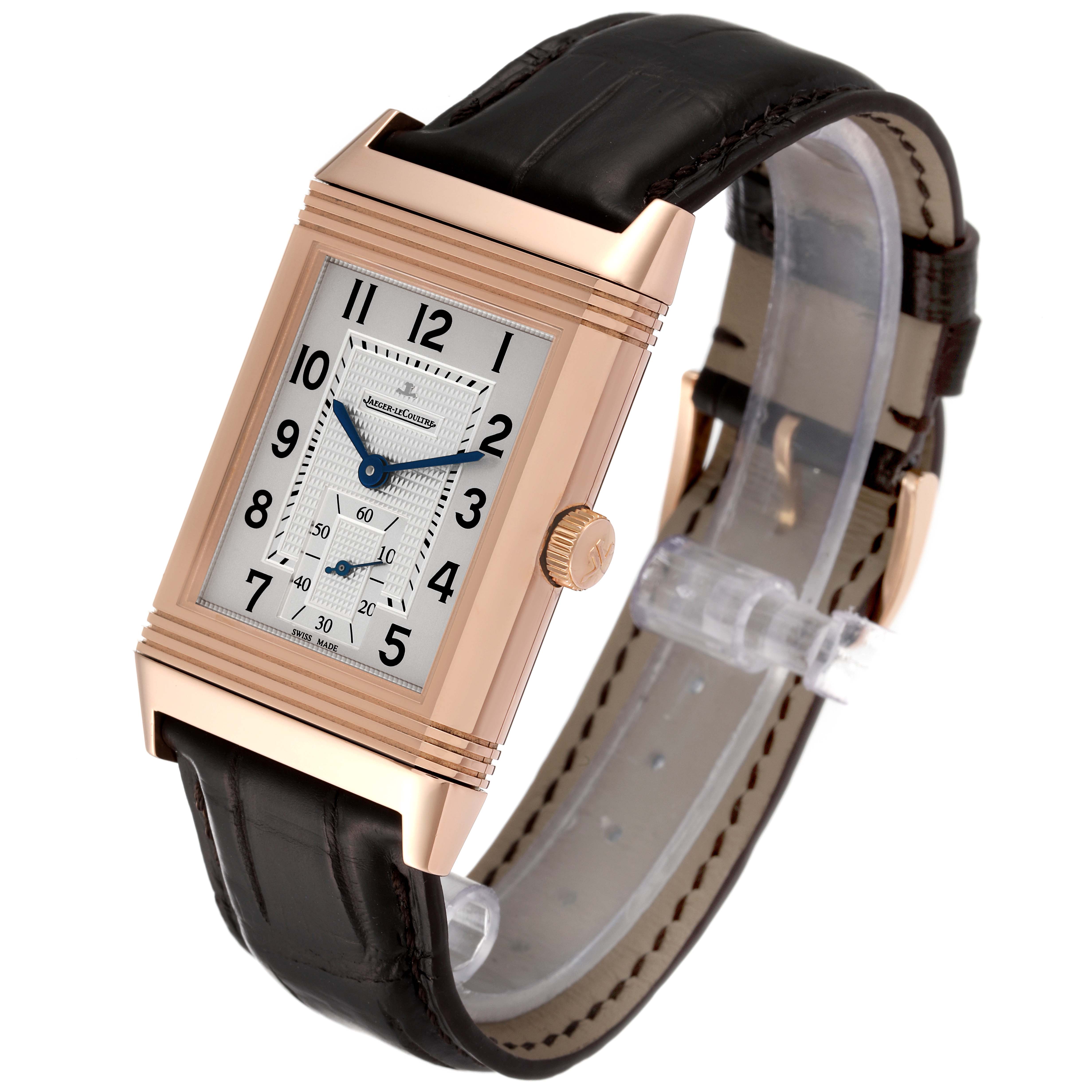 This image shows a Jaeger LeCoultre Reverso Q3732420 Men's Rose Gold Silver Dial Q3732420 Men's Rose Gold Silver Dial watch at an angle displaying its rectangular face, crown, and leather strap.