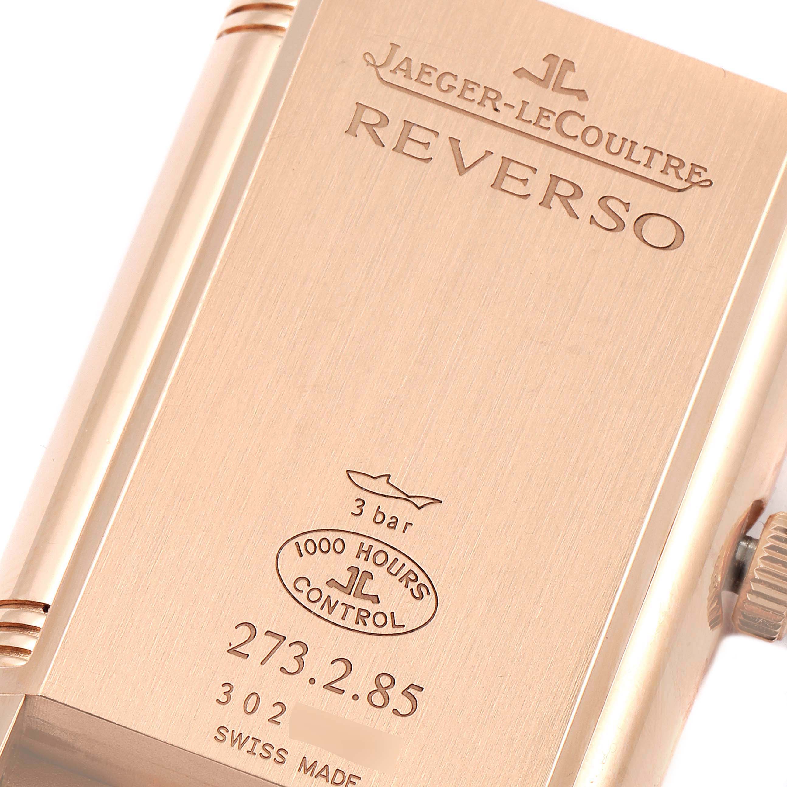 The image shows the case back of a Jaeger-LeCoultre Reverso watch, highlighting its engravings and serial numbers at a close angle.