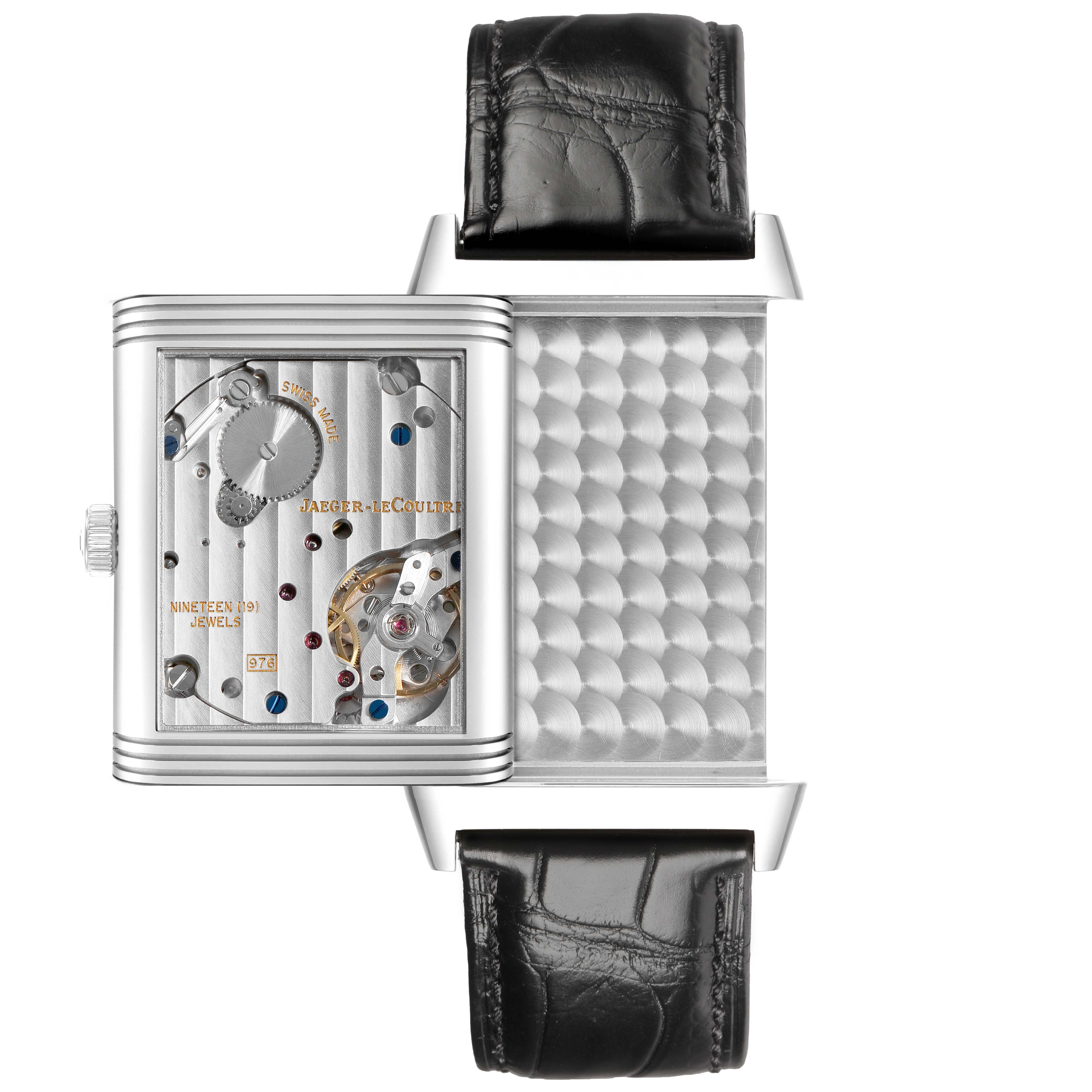 The Jaeger-LeCoultre Reverso watch is shown from a top angle, highlighting its open back and inner mechanics.