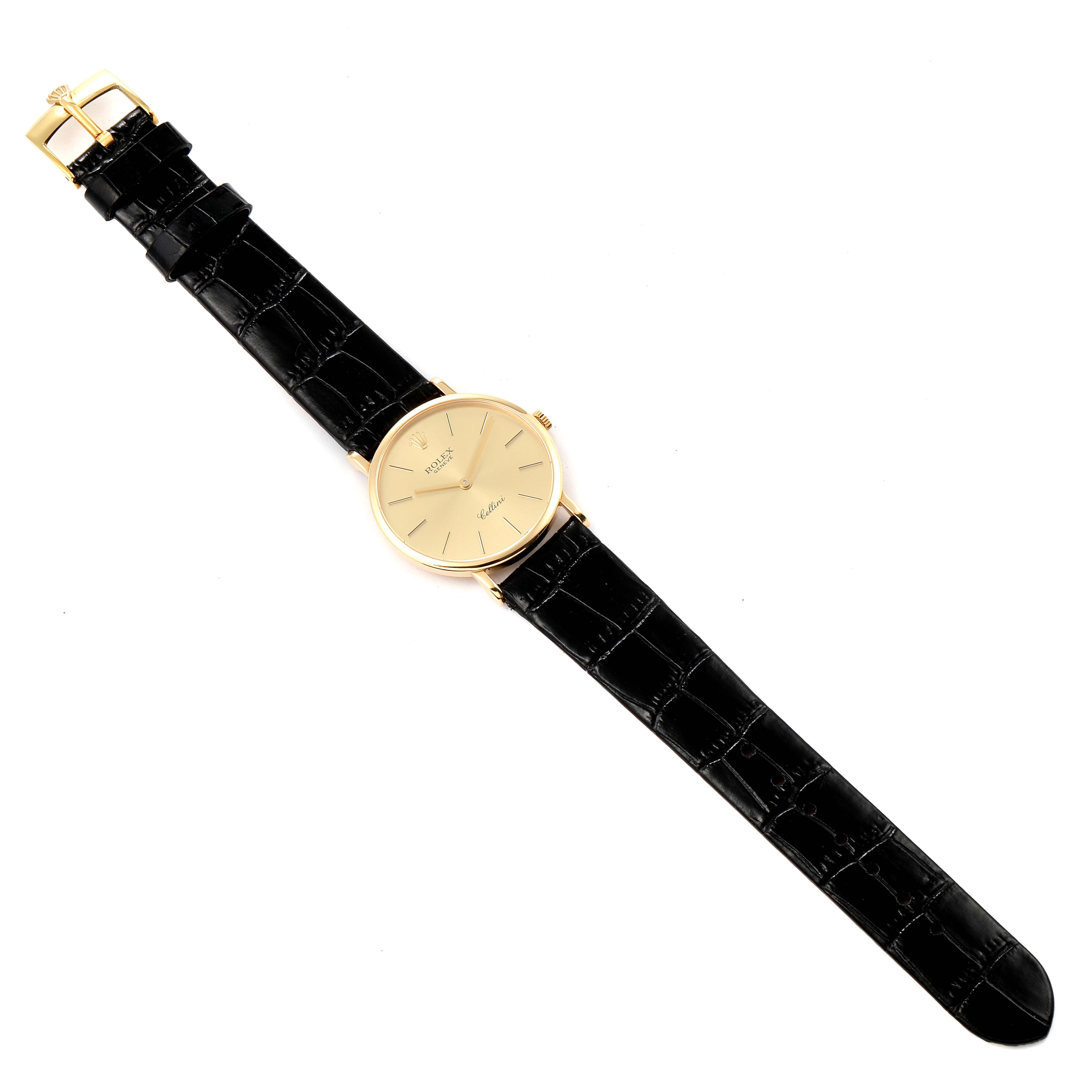 The image shows a top view of the Rolex Cellini 5112 Men's Yellow Gold Champagne Dial 5112 Men's Yellow Gold Champagne Dial watch, including its black leather strap and gold-tone face.