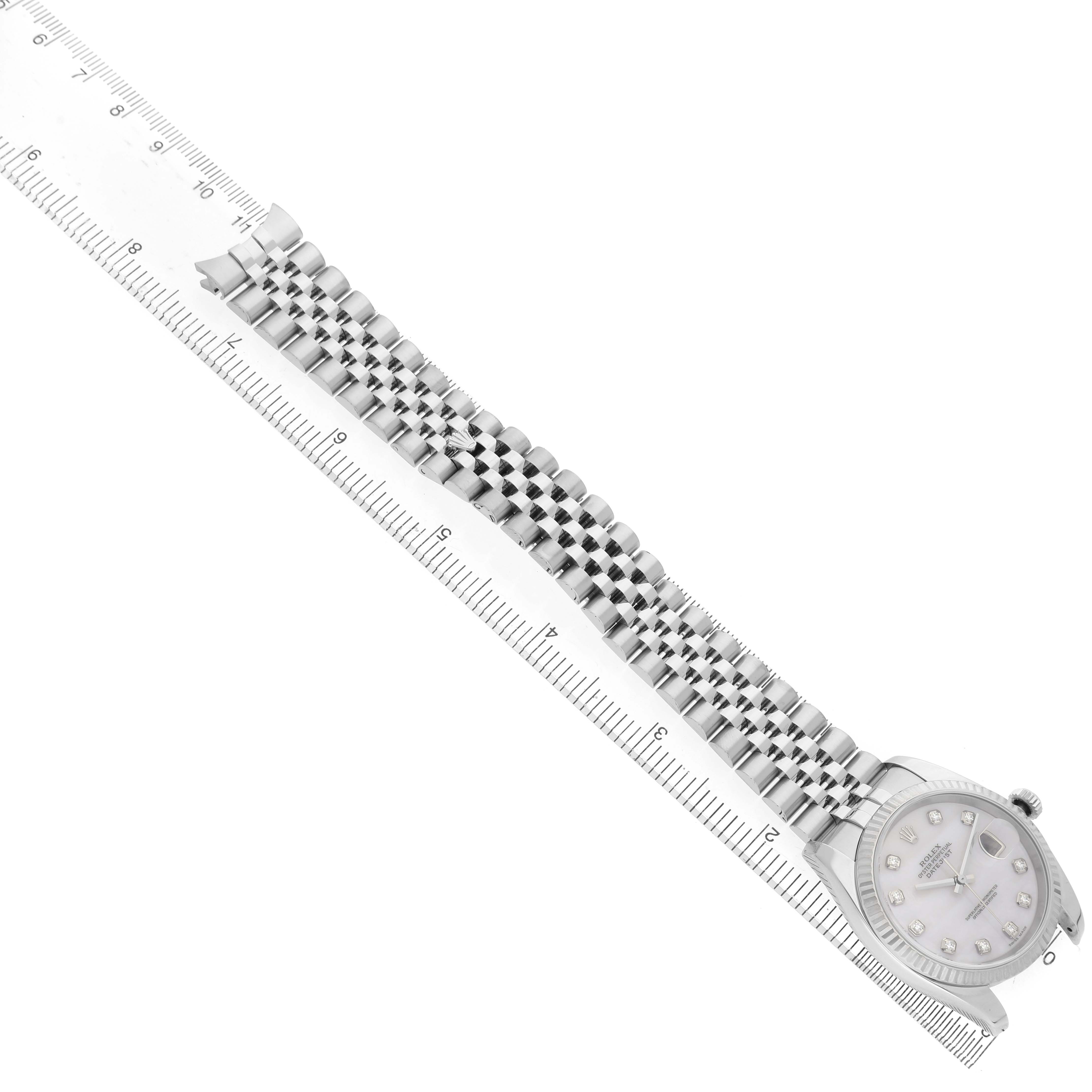 The Rolex Datejust 116234 Men's Stainless Steel Mother of Pearl Dial watch is displayed from above, showcasing the bracelet and part of the dial alongside a ruler for scale.