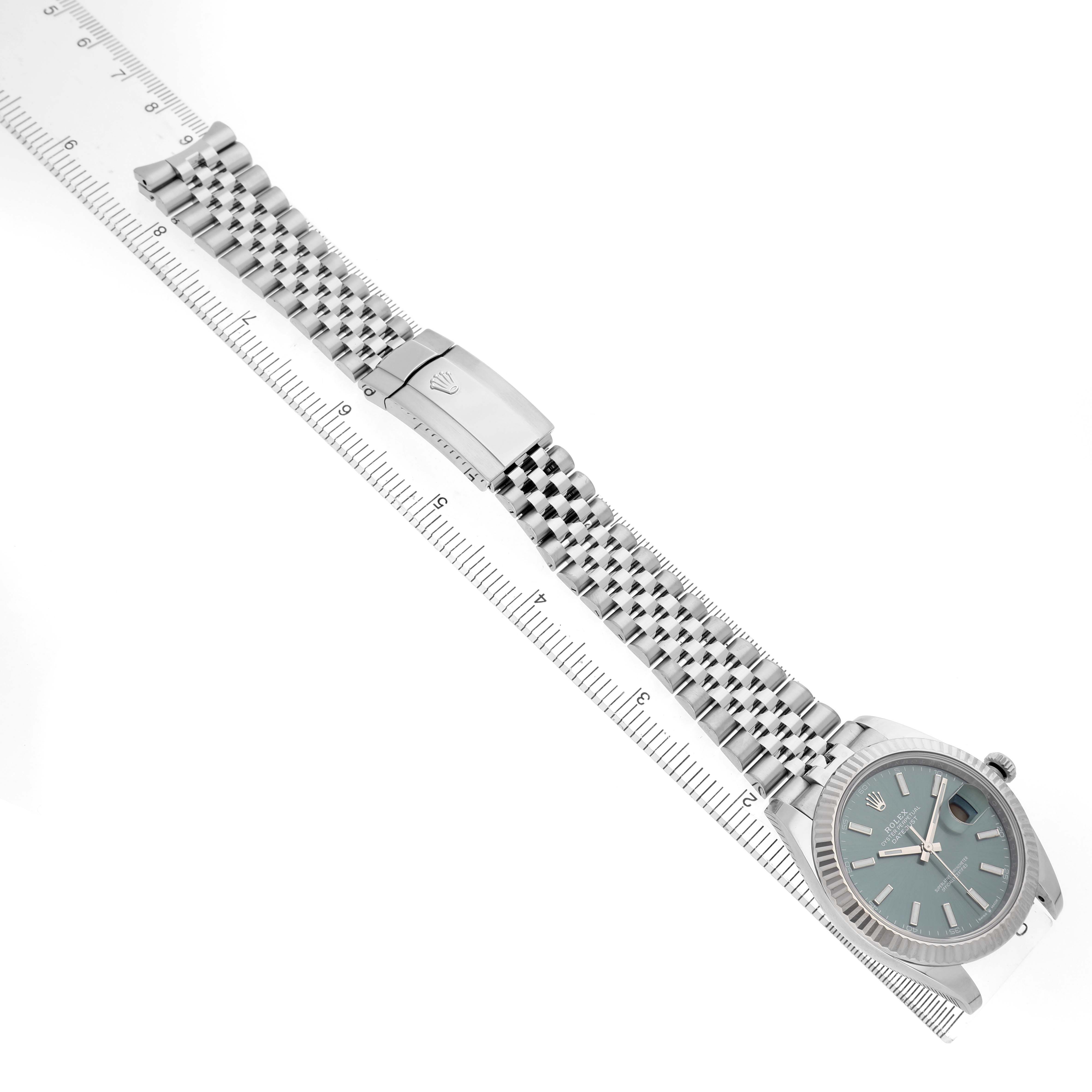 The image shows the Rolex Datejust 41 126334 Men's Stainless Steel Green Dial watch angled with the face, bracelet, and clasp visible, alongside a ruler.