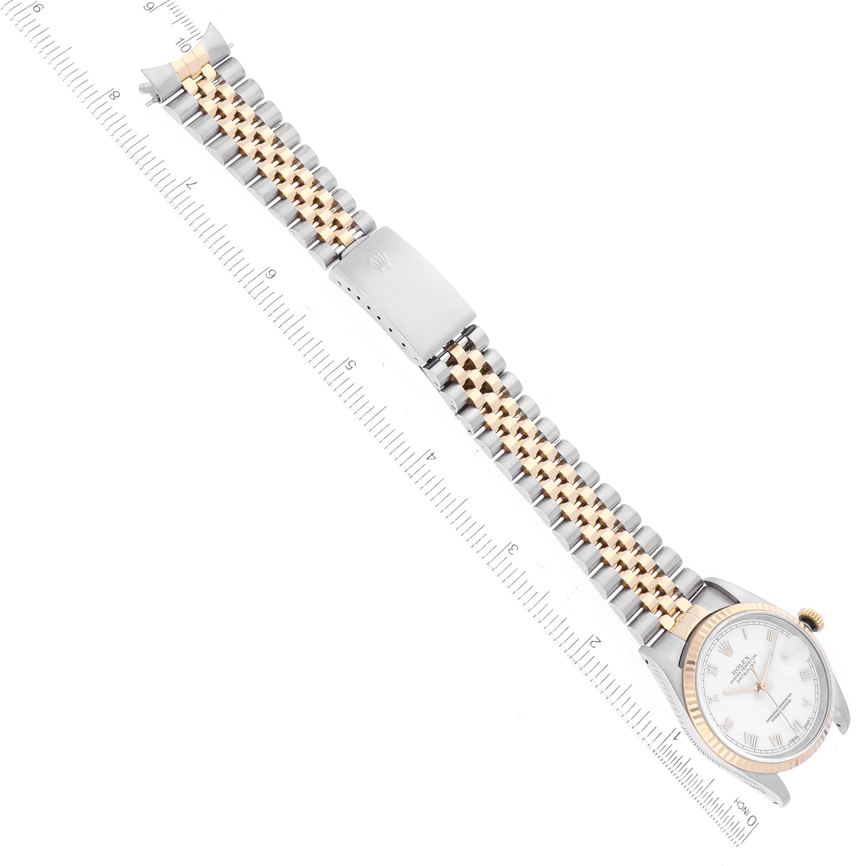 The Rolex Datejust 16233 Men's Steel and Gold (two tone) White Dial 16233 Men's Steel and Gold (two tone) White Dial watch is shown from an overhead angle highlighting the face, case, and two-tone metal bracelet with a ruler for scale.