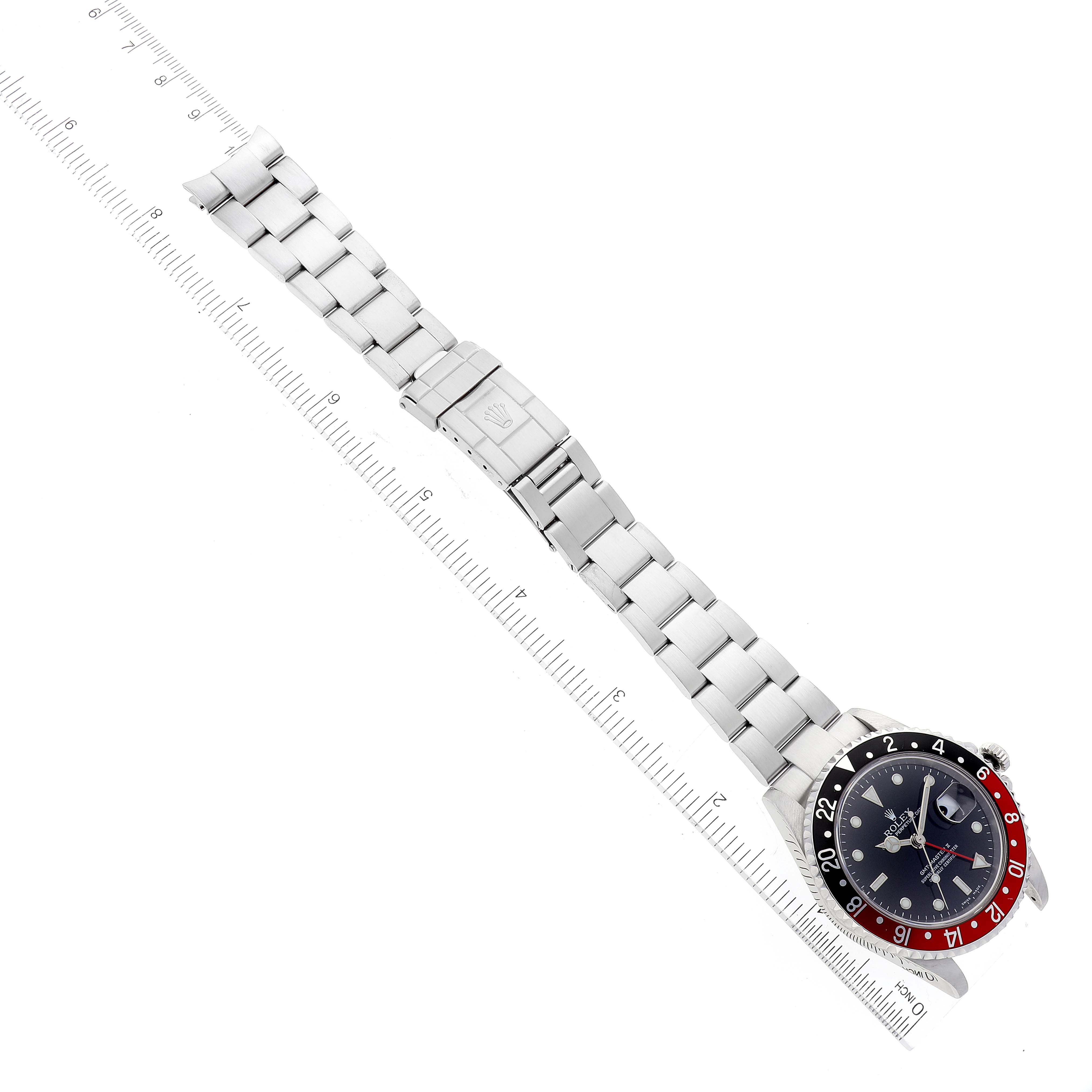The Rolex GMT-Master 16710 Men's Stainless Steel Black Dial 16710 Men's Stainless Steel Black Dial watch is shown fully extended, including the bracelet and clasp, with a ruler for scale.