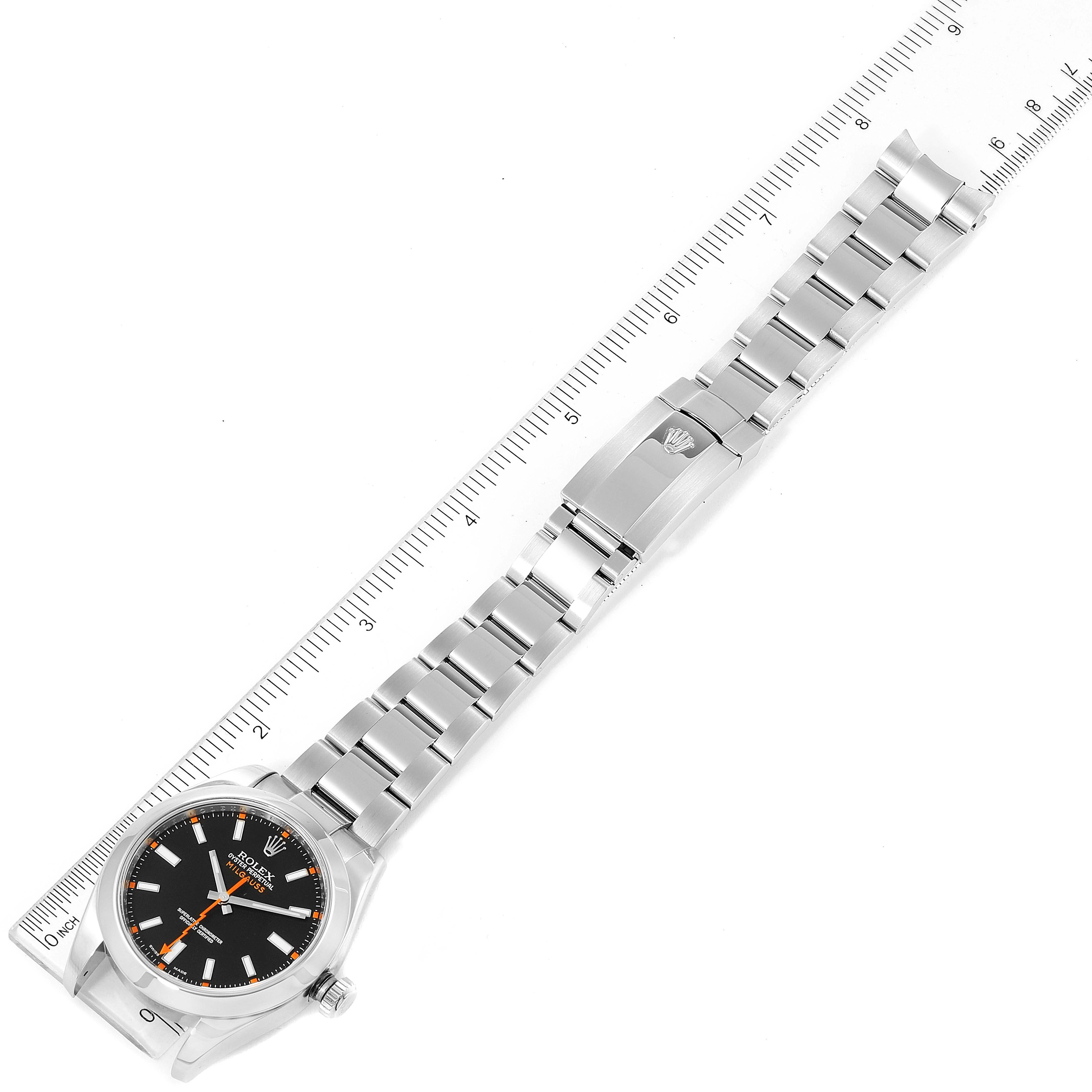 The image shows a top-down view of a Rolex Milgauss 116400 Men's Stainless Steel Black Dial 116400 Men's Stainless Steel Black Dial watch with its full metal bracelet and clasp, next to a ruler for scale.