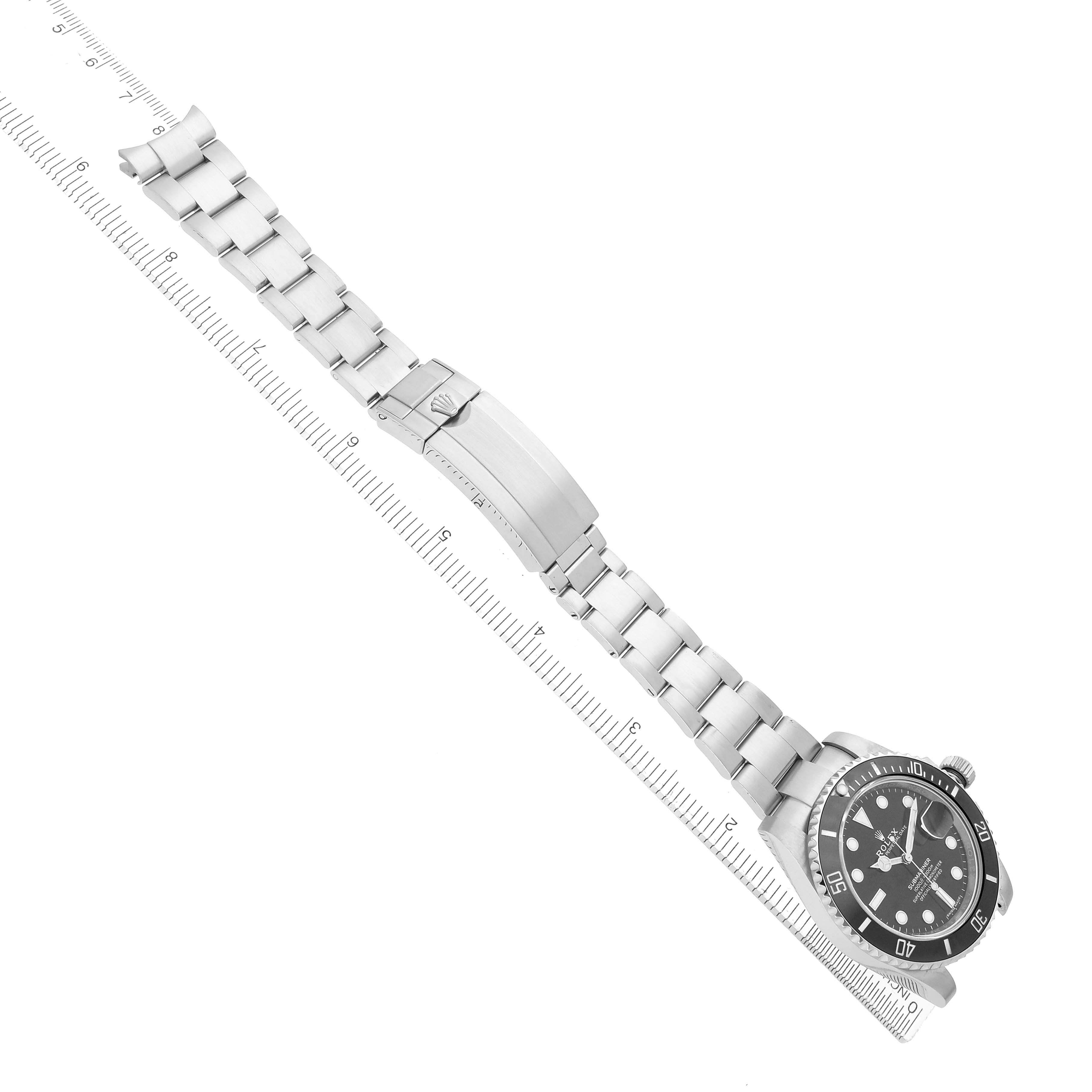 The image shows a Rolex Submariner 116610 Men
s Stainless Steel Black Dial watch laid flat, displaying its face, bezel, bracelet, and clasp diagonally beside a ruler.