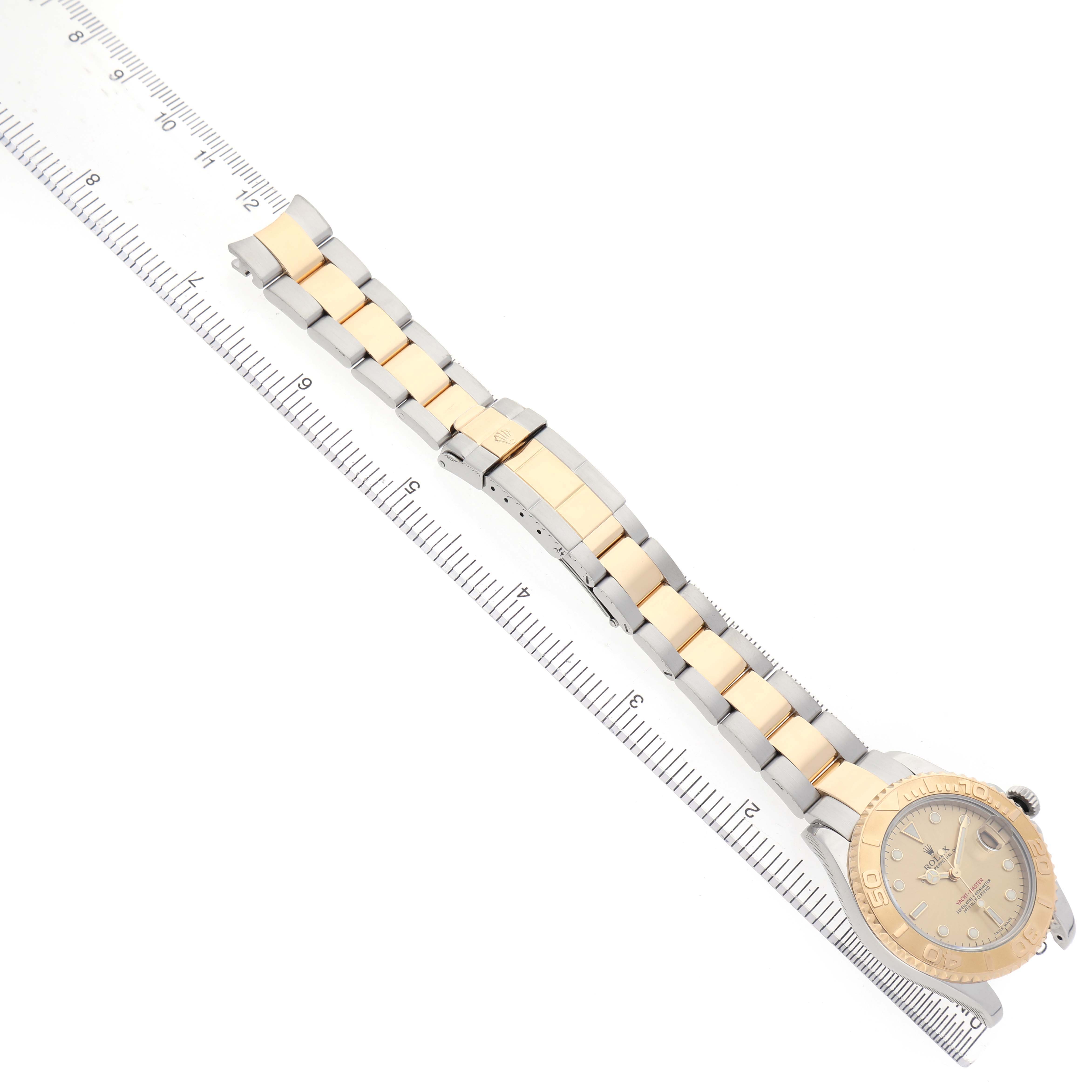 The Rolex Yacht-Master 168623 Men's Steel and Gold (two tone) Champagne Dial watch is shown from a top angle, displaying the full band and face, with a ruler for scale.