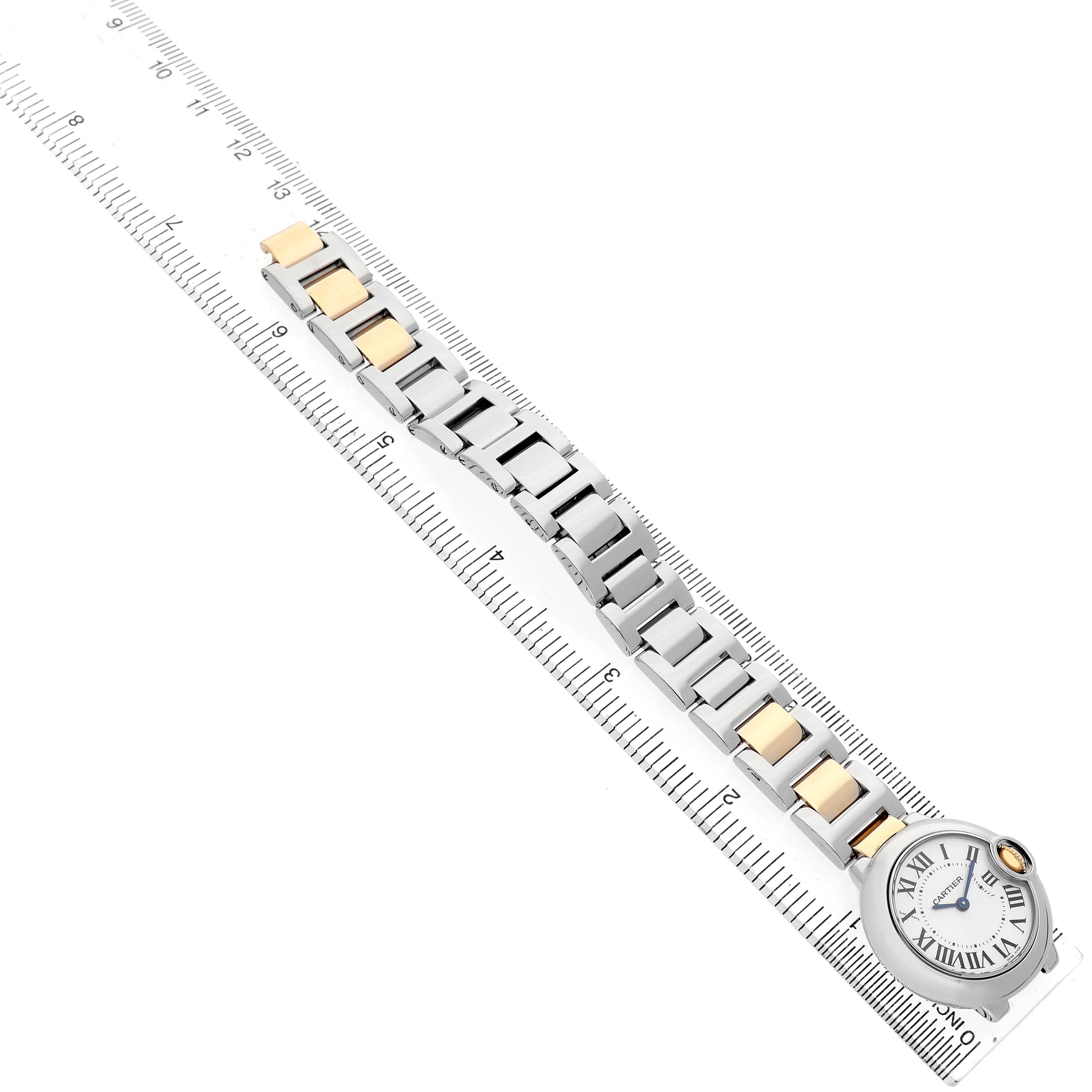 The image shows the Cartier Ballon Bleu W69007Z3 Women's Steel and Gold (two tone) Silver Dial watch laid diagonally on a ruler, displaying its face and metal bracelet with mixed-links.