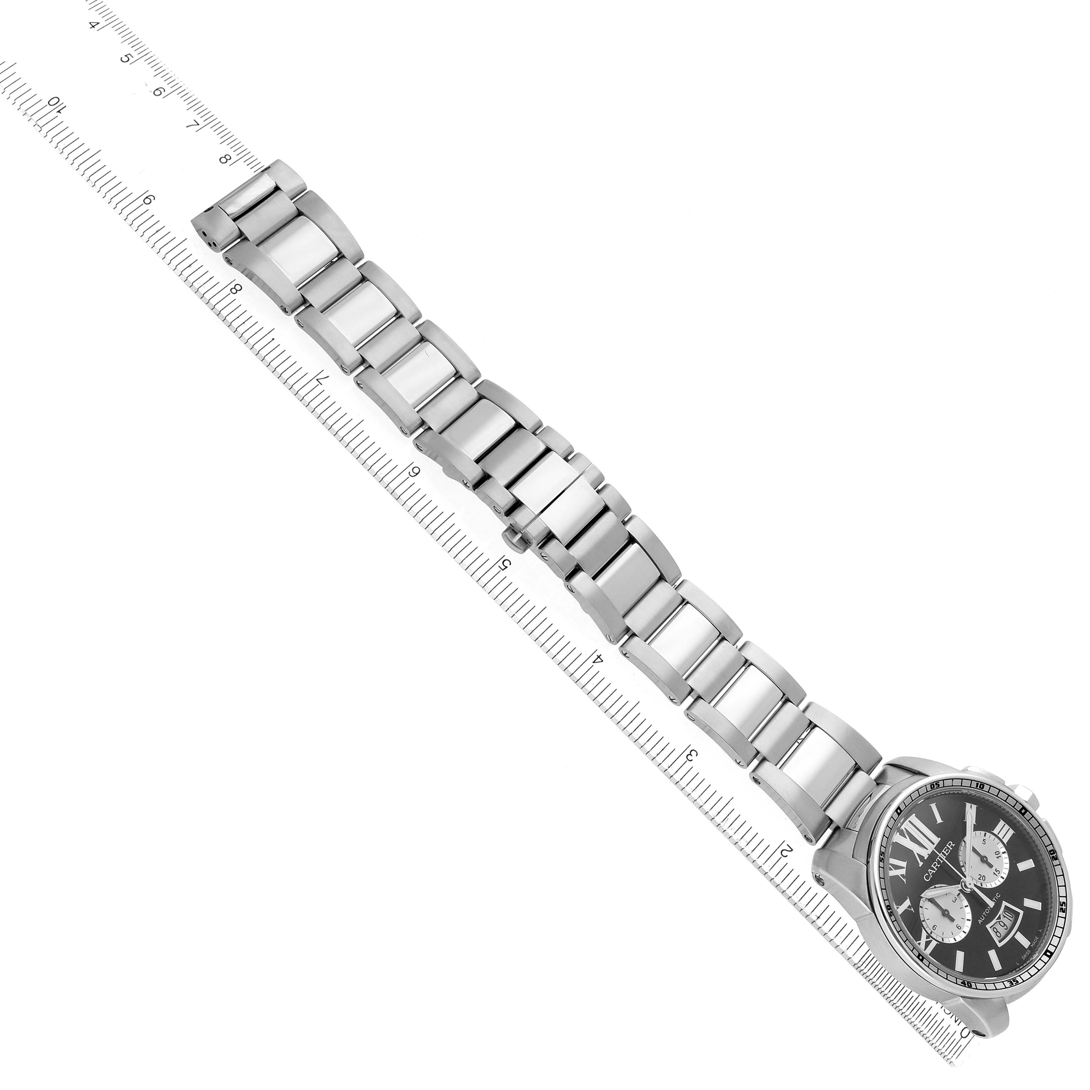 The image shows the Calibre de Cartier watch by Cartier at an oblique angle, highlighting the watch face and bracelet alongside a ruler.