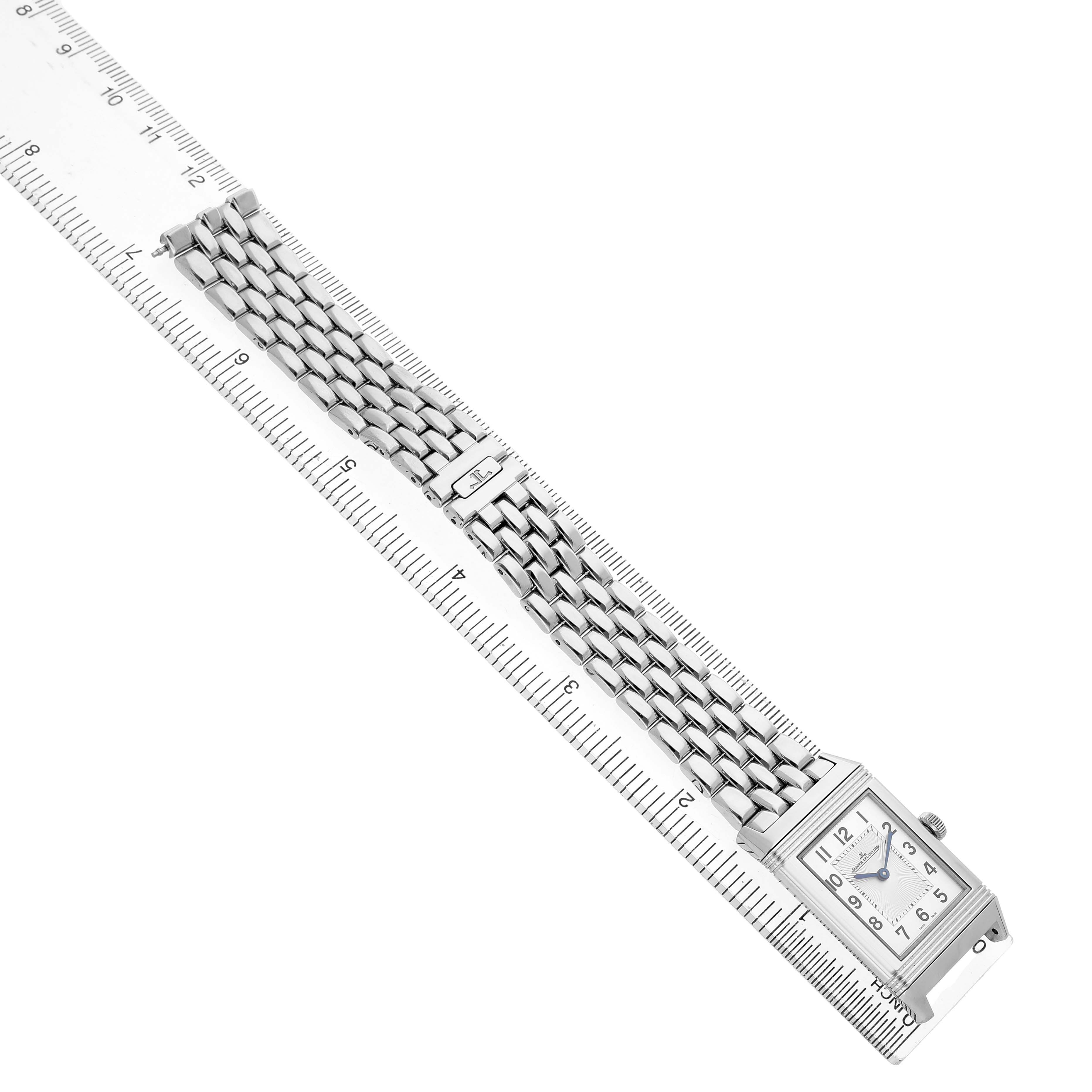 The Jaeger LeCoultre Reverso Q2548120 Men's Stainless Steel Silver Dial watch is shown with a front view, highlighting the dial, bracelet, and deployment clasp, laid along a ruler.