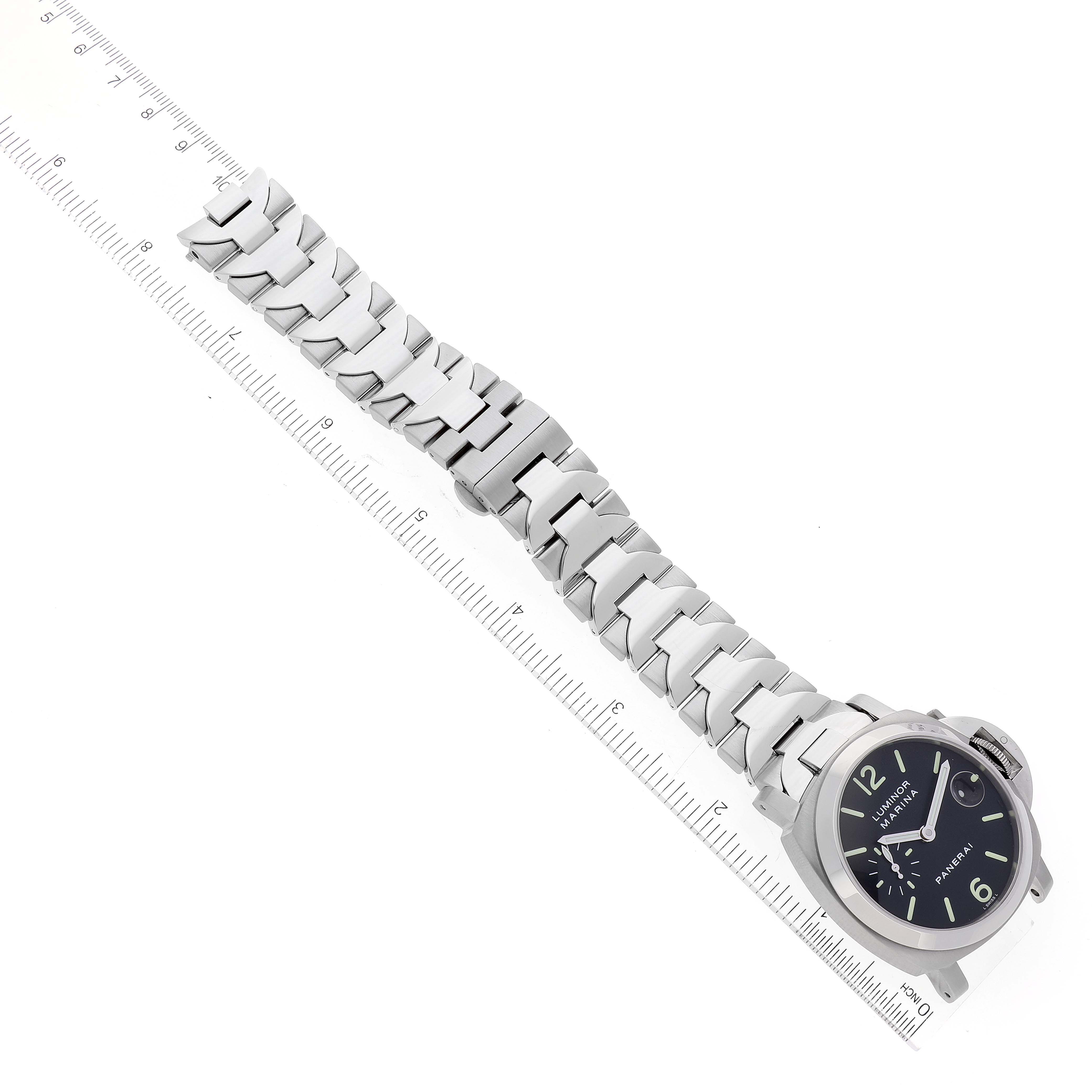 The image shows a Panerai Luminor PAM00050 Men
s Stainless Steel Black Dial PAM00050 Men
s Stainless Steel Black Dial watch at an oblique angle, highlighting the face and metal bracelet laid alongside a ruler.