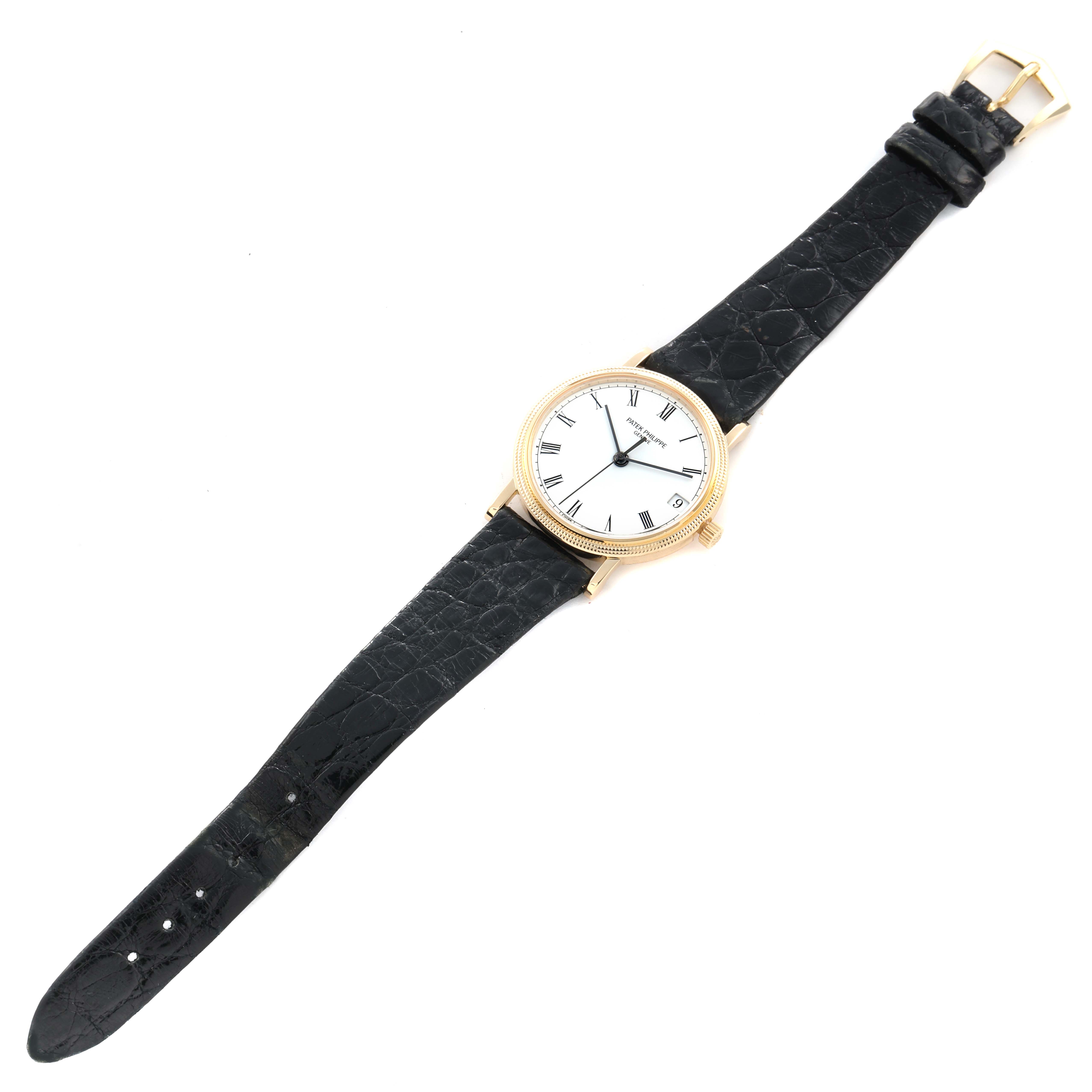 The Patek Philippe Calatrava 3802J Men
s Yellow Gold White Dial watch is shown from a top-down angle, displaying the entire face, bezel, and black leather strap.