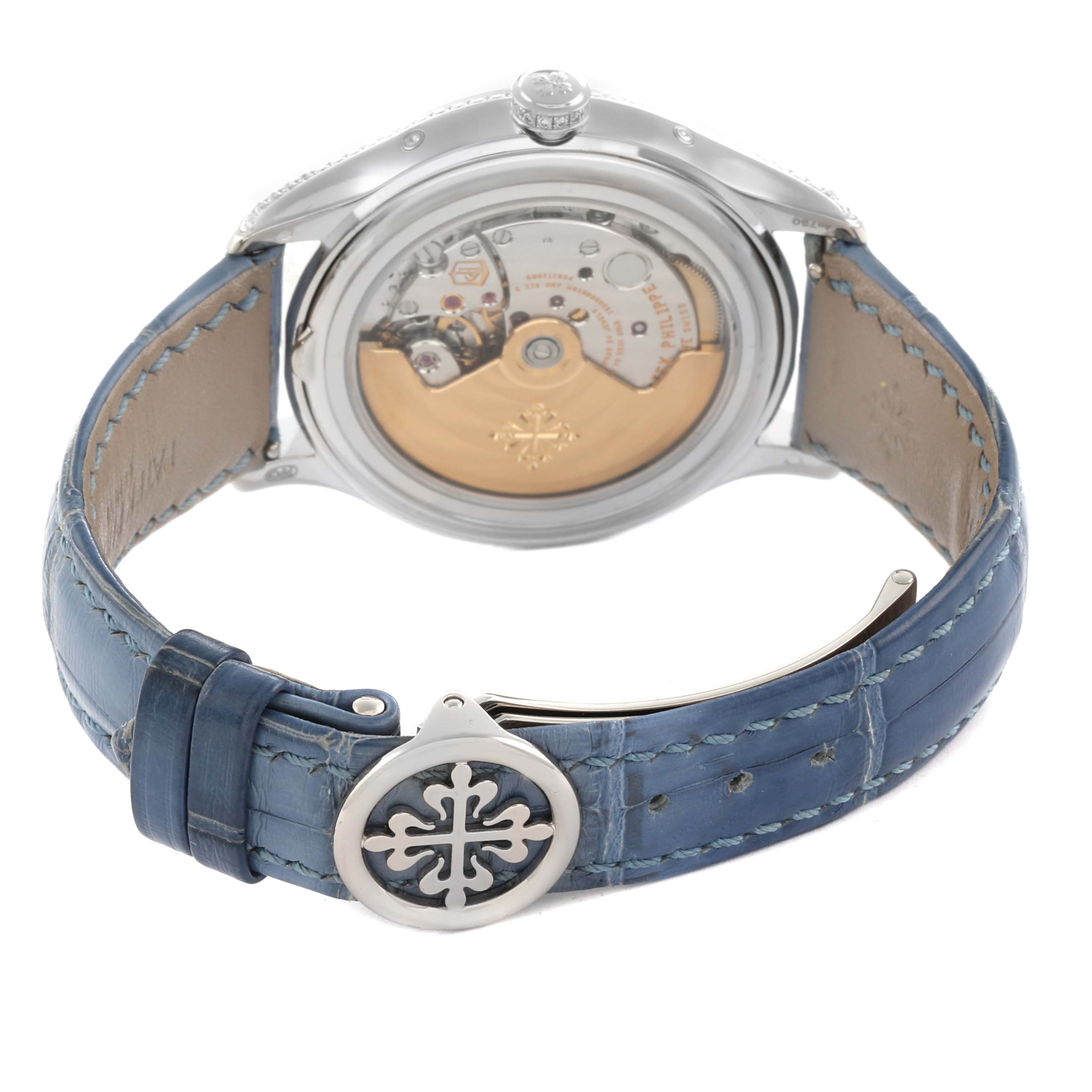 The image shows the back of a Patek Philippe Complications 4947G-001 Men
s White Gold Blue Dial watch, with visible movement and a blue leather strap unfolded.