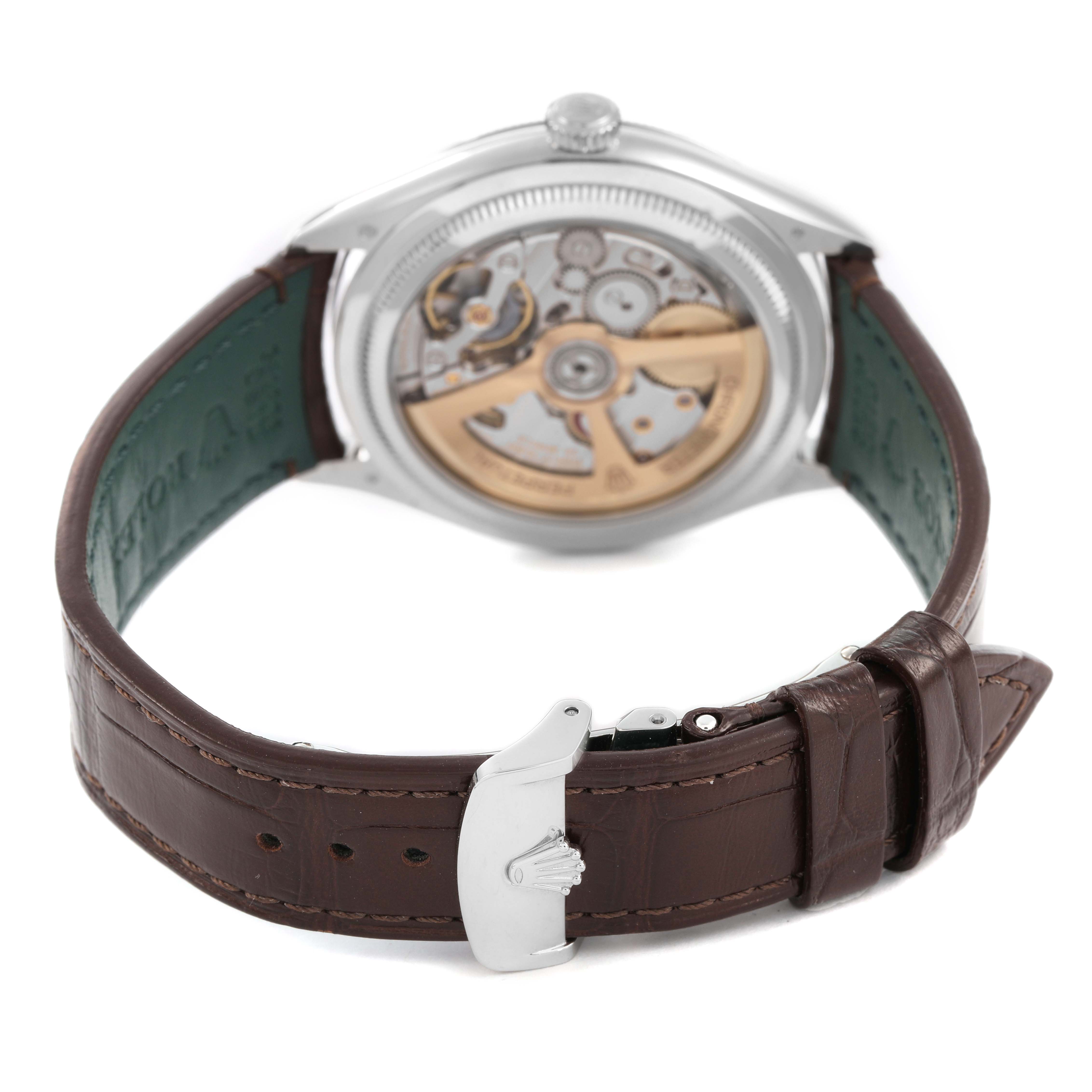 The image shows the back of a Rolex 1908 52506 Men's Platinum Blue Dial model watch, revealing its movement and brown leather strap with a clasp.