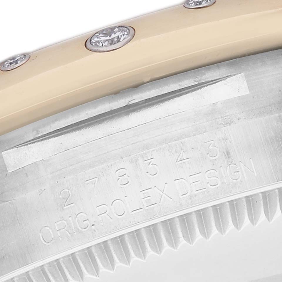 The image shows a side view of a Rolex Datejust 278343 Women's Steel and Gold (two tone) Mother of Pearl Dial, focusing on the bezel with diamonds and part of the case with engraved text.