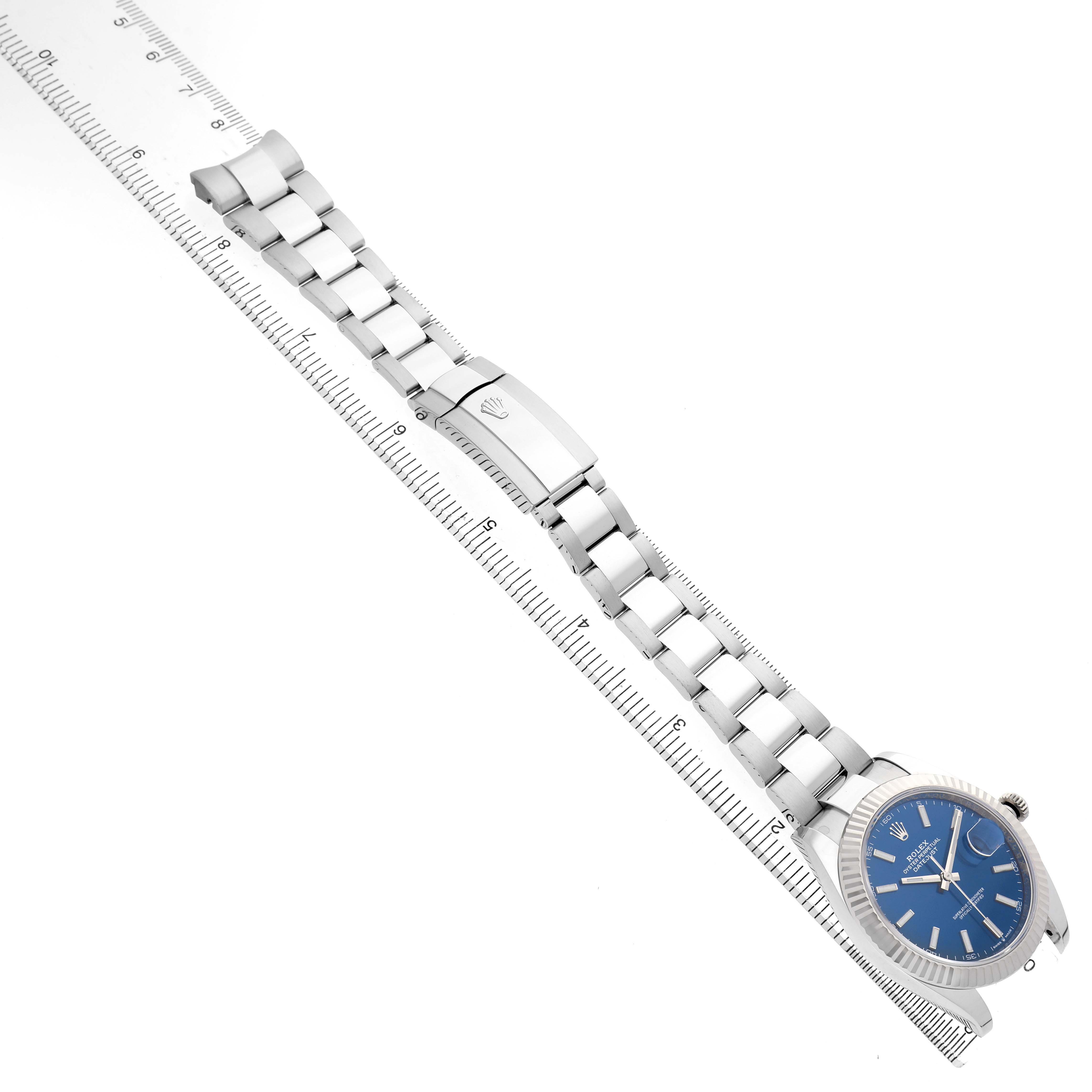 The Rolex Datejust 41 126334 Men's Stainless Steel Blue Dial watch is shown at a slight angle, displaying the dial, bezel, and bracelet alongside a measuring ruler.