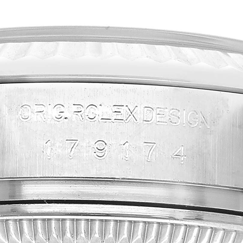 The image shows a close-up of the Datejust model by Rolex, focusing on the engraved design and fluted bezel.