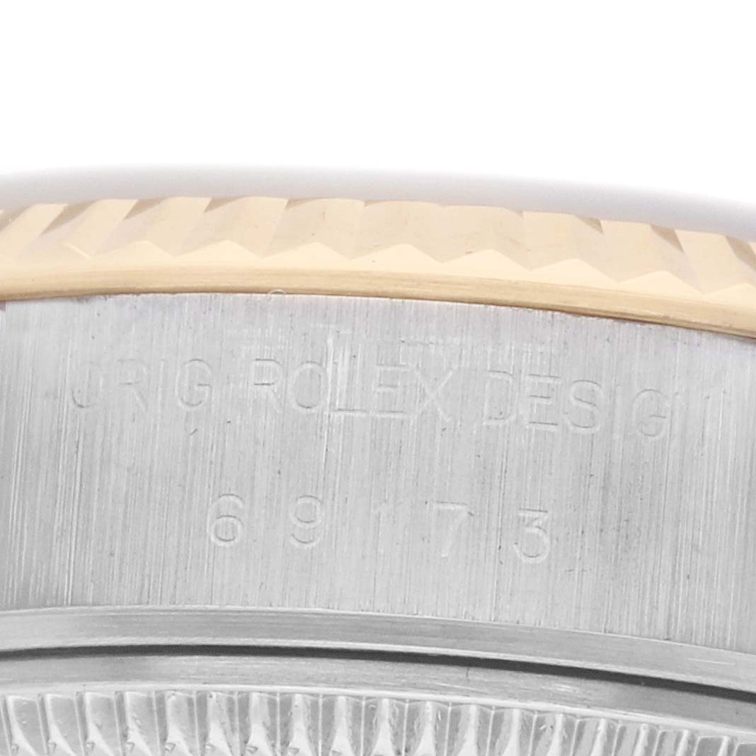 The image shows a close-up side view of the Rolex Datejust 69173 Women's Steel and Gold (two tone) Champagne Dial watch’s case with focus on the bezel and engravings.