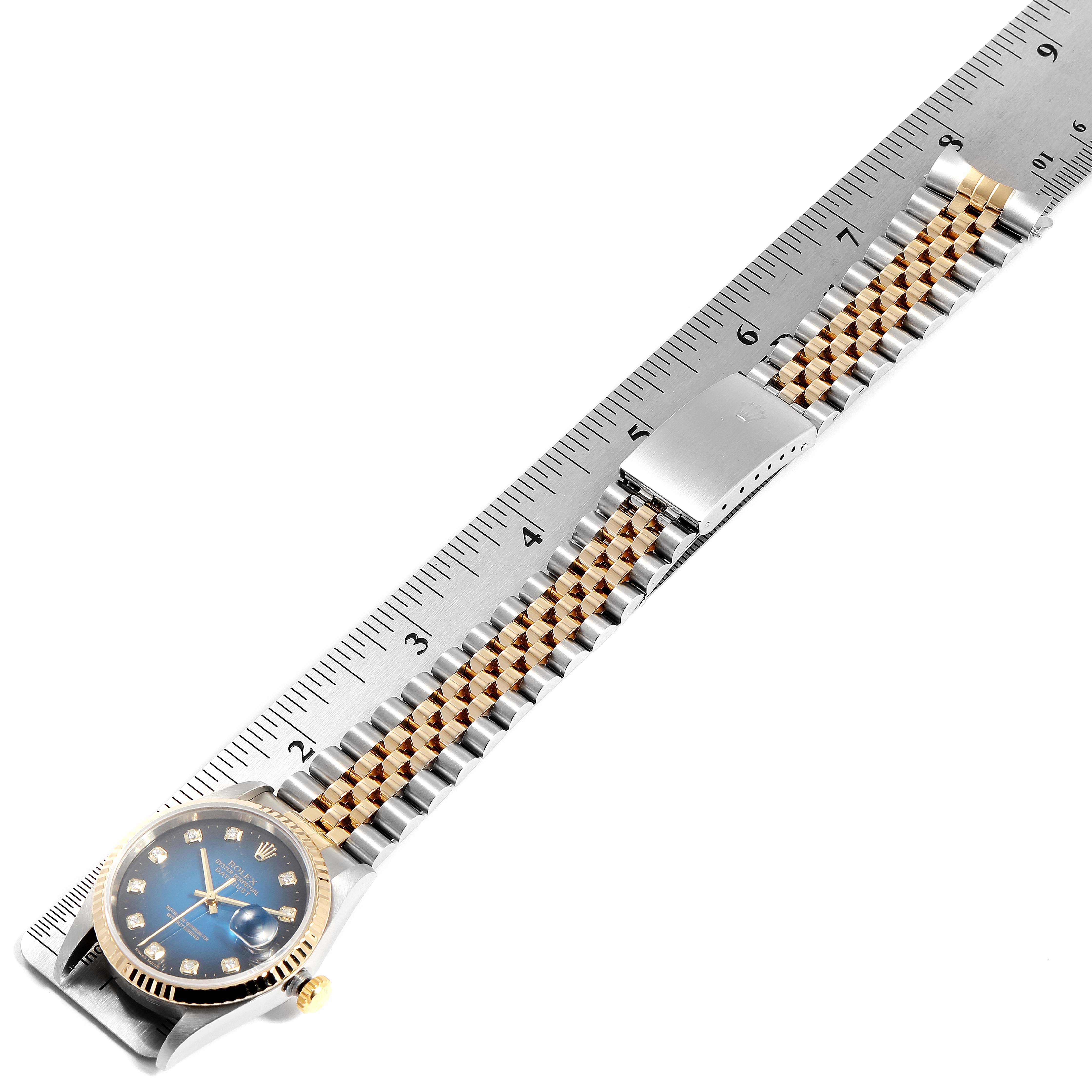 This image shows a Rolex Datejust 16233 Men's Steel and Gold (two tone) Blue Dial 16233 Men's Steel and Gold (two tone) Blue Dial watch with a blue dial, gold fluted bezel, and a two-tone Jubilee bracelet next to a ruler.