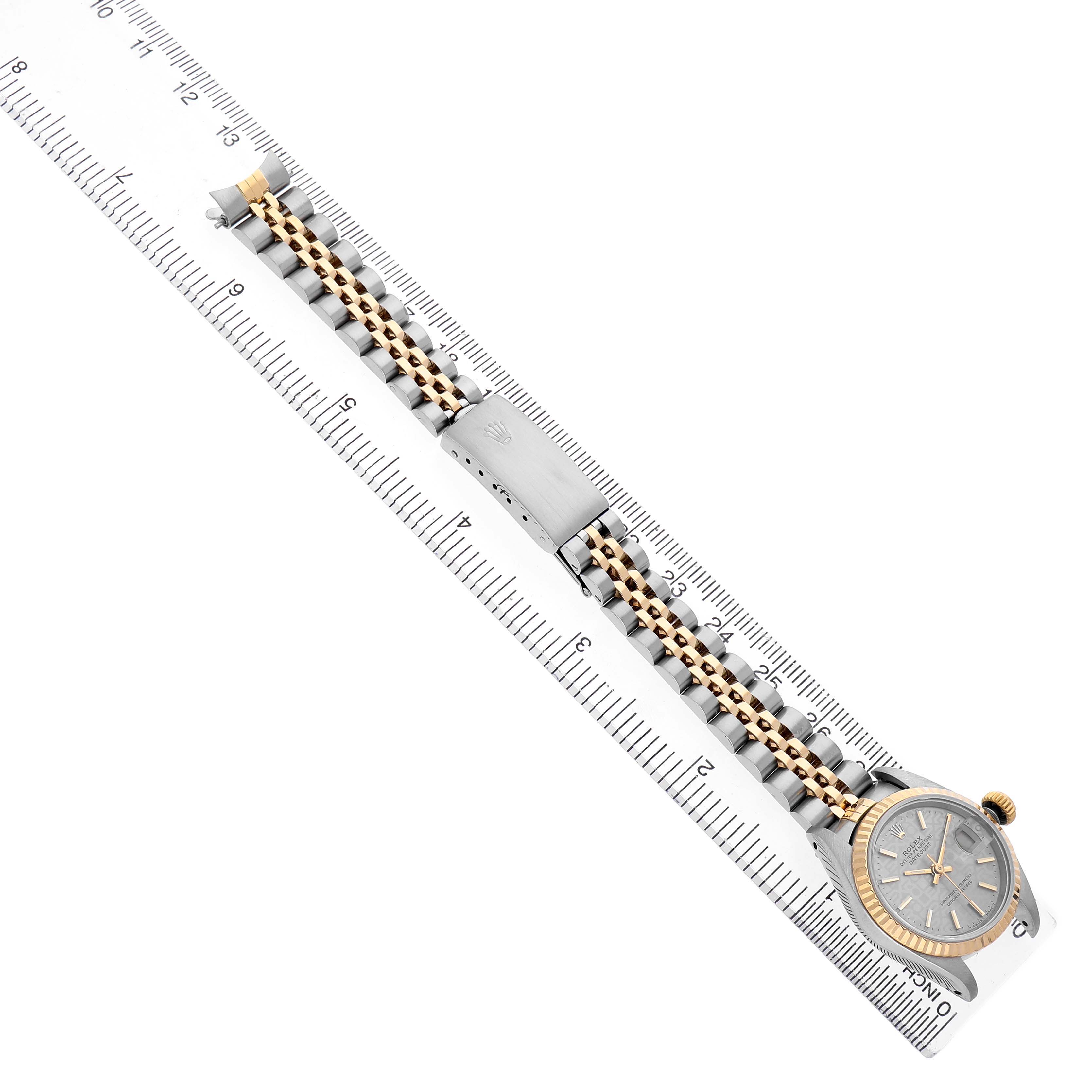 The Rolex Datejust 69173 Women's Steel and Gold (two tone) Silver Dial watch is shown from an overhead angle, displaying the full strap, clasp, and face alongside a ruler.