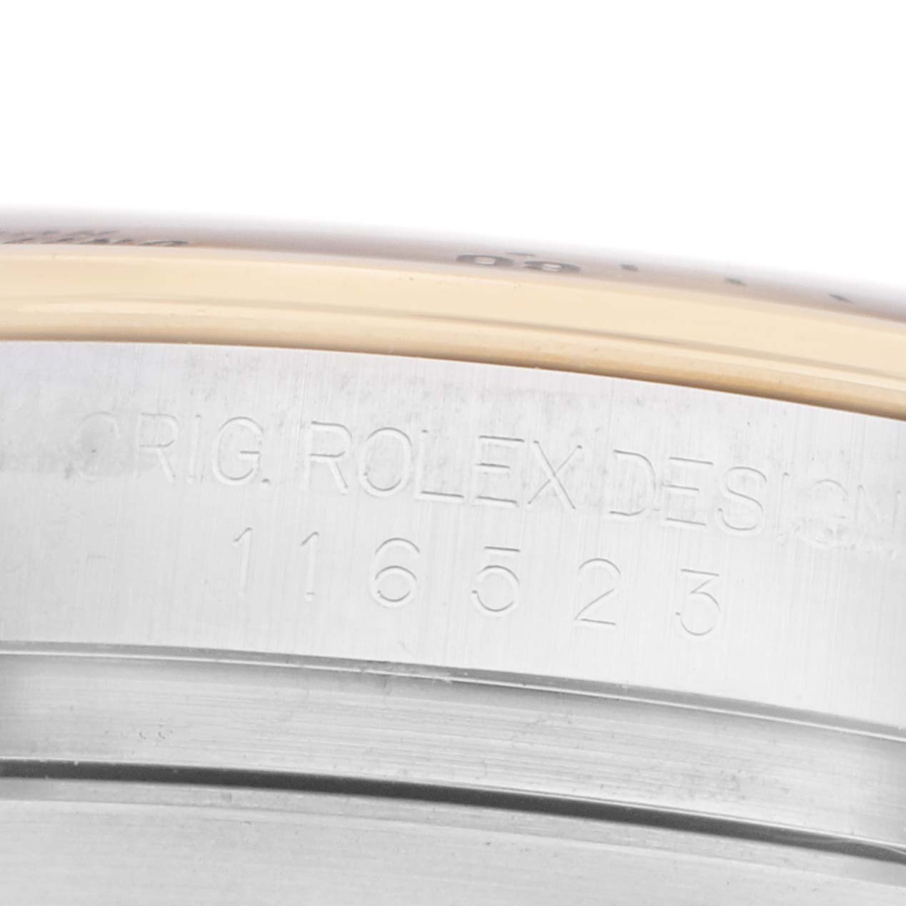 The image shows a close-up of the side of a Rolex Daytona 116523 Men
s Steel and Gold (two tone) Black Dial, highlighting the engraved model number.
