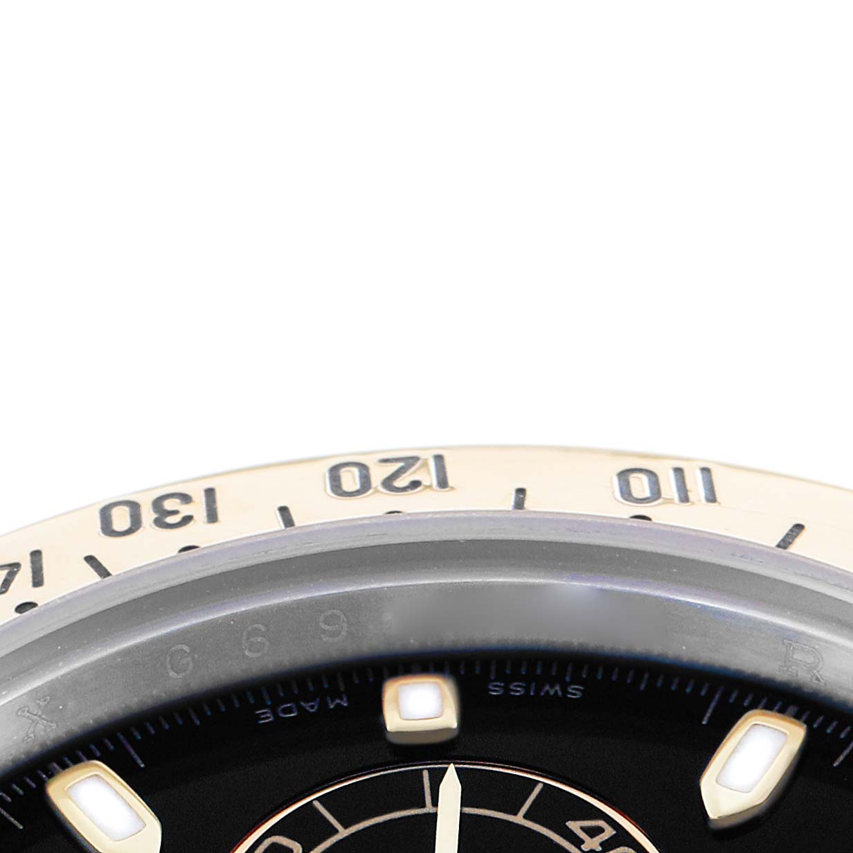 The image shows a close-up of the Rolex Daytona 116523 Men
s Steel and Gold (two tone) Black Dial
s bezel and part of the dial from a top angle.