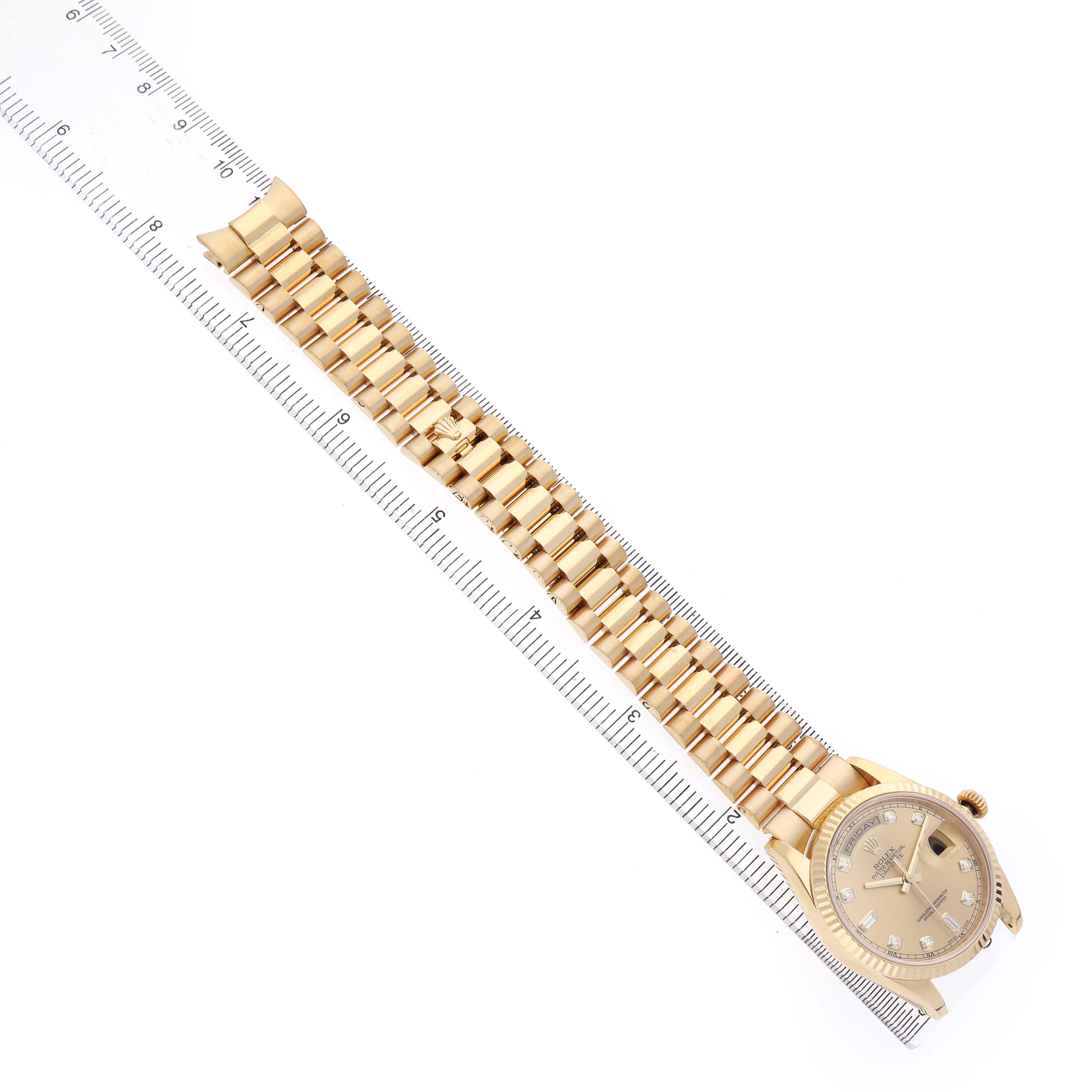 The Rolex President 118238 Men's Yellow Gold Champagne Dial watch is shown from a top-down angle, highlighting the face, bracelet, and clasp alongside a ruler.