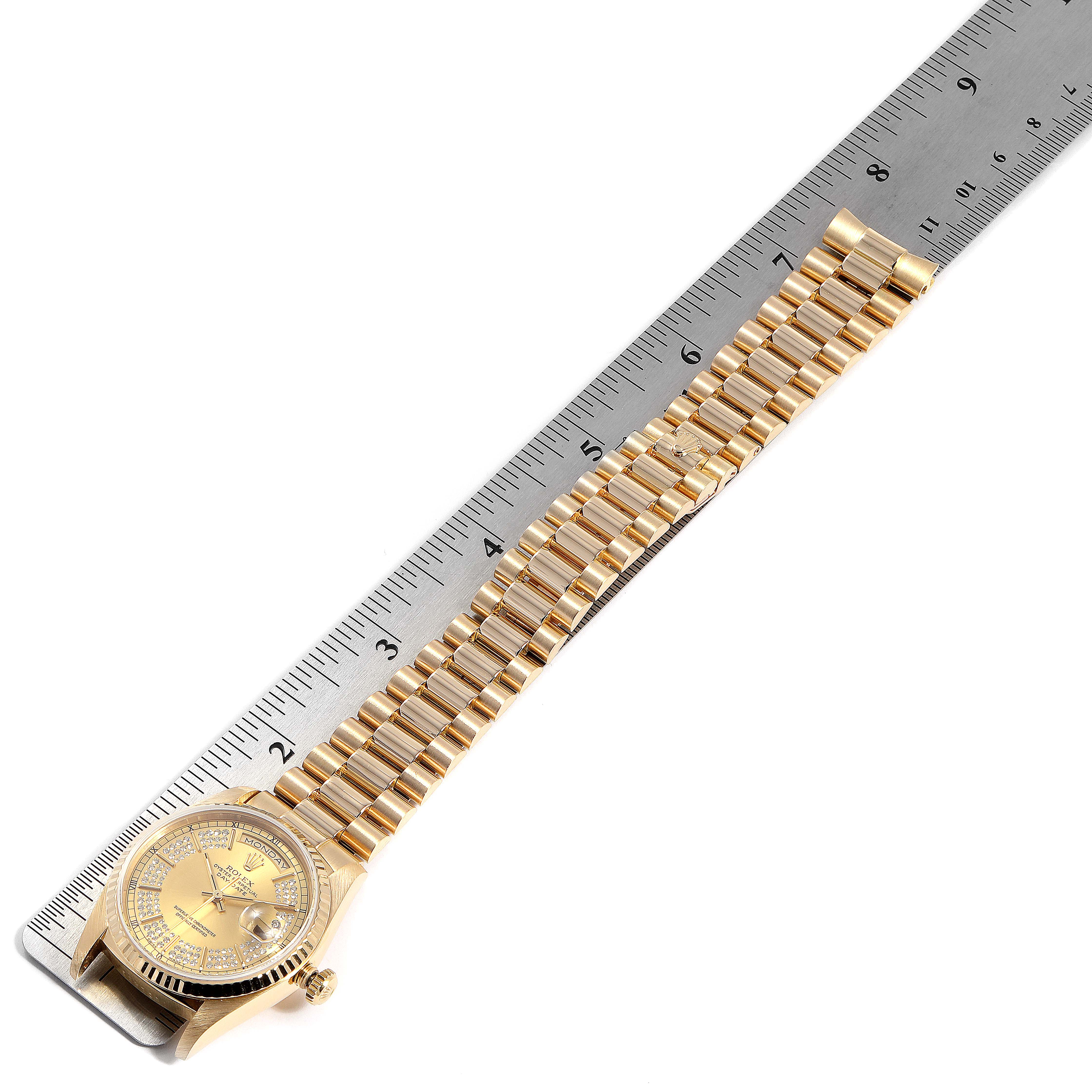 The image shows a Rolex President 18238 Men
s Yellow Gold Champagne Dial 18238 Men
s Yellow Gold Champagne Dial model watch laid flat next to a ruler, displaying the full bracelet and watch face at an angled perspective.