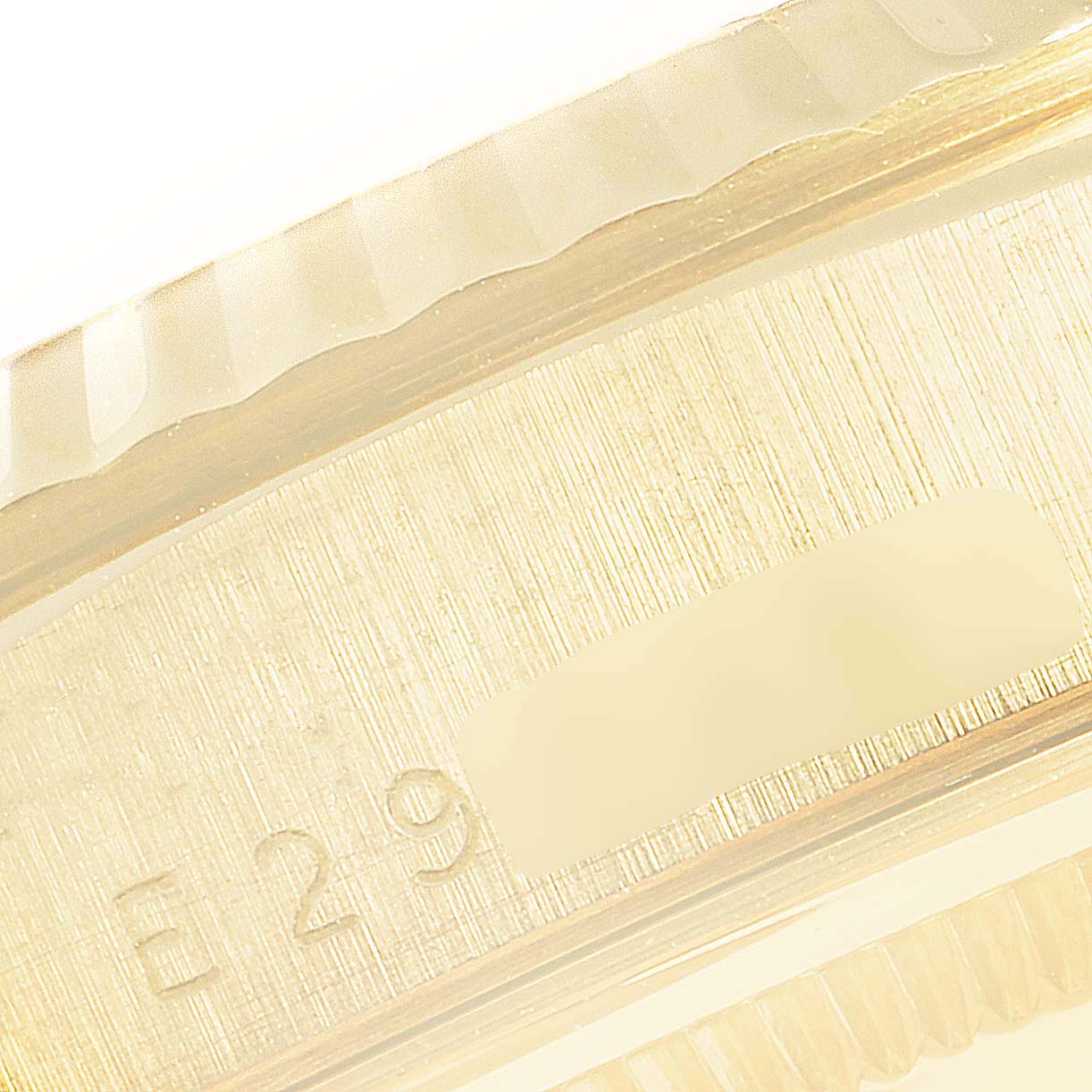 This close-up image shows the side of the gold case of a Rolex President 18238 Men
s Yellow Gold Champagne Dial 18238 Men
s Yellow Gold Champagne Dial model watch, displaying part of its serial number.