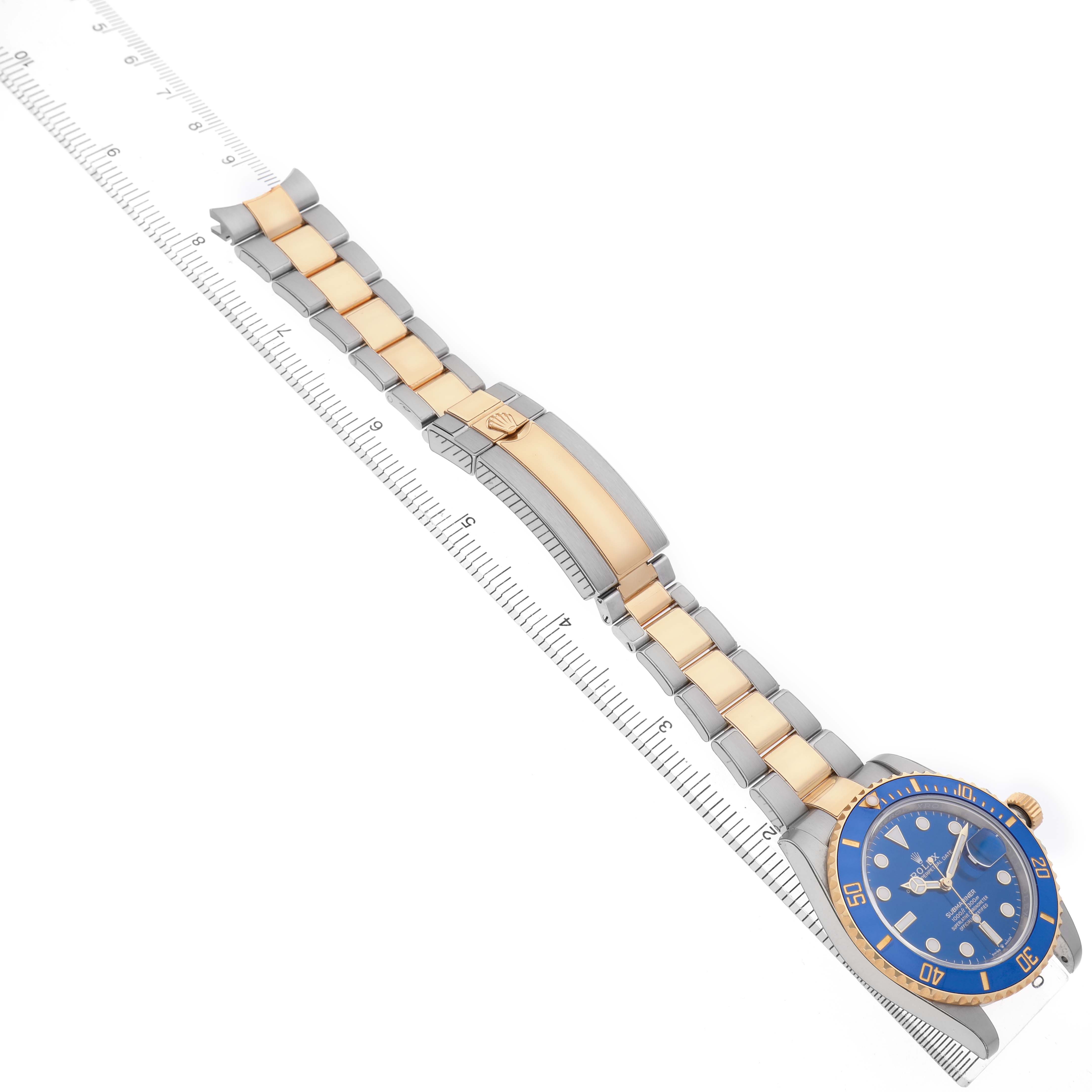 The Rolex Submariner 126613LB Men's Steel and Gold (two tone) Blue Dial watch is shown from a top angle, displaying the face, bezel, and full bracelet aligned with a ruler.