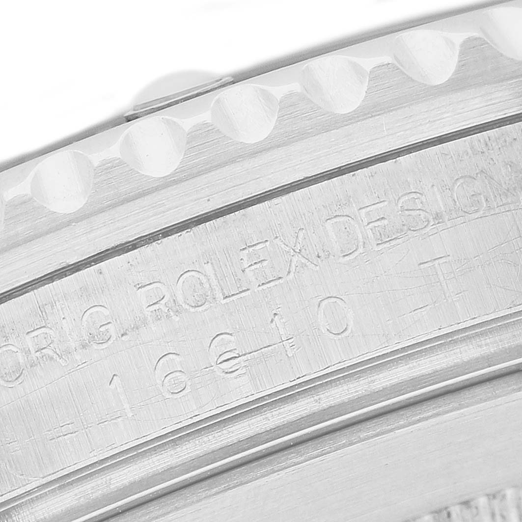 The image shows a close-up of the engraved side of a Rolex Submariner 16610 Men's Stainless Steel Black Dial, highlighting its bezel indentations and model details.