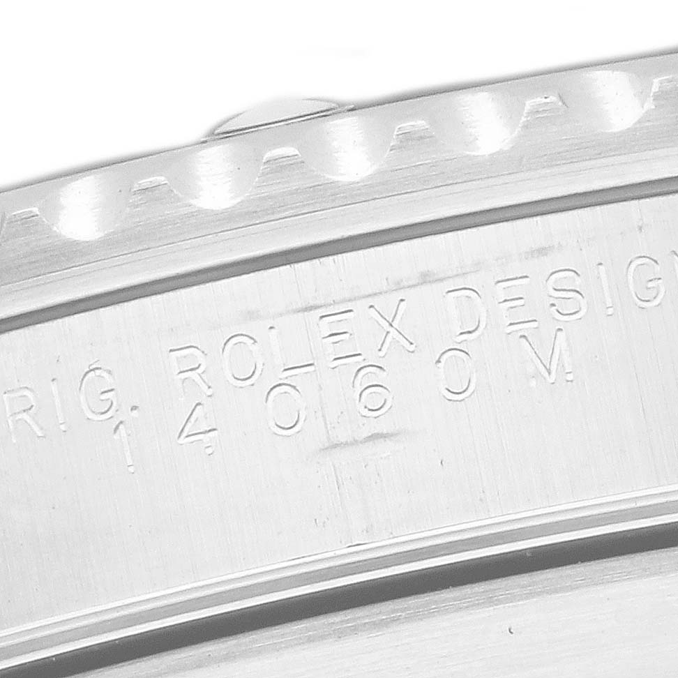The image shows a close-up of the side case of a Rolex Submariner 14060M Men
s Stainless Steel Black Dial, highlighting its engraved design details.
