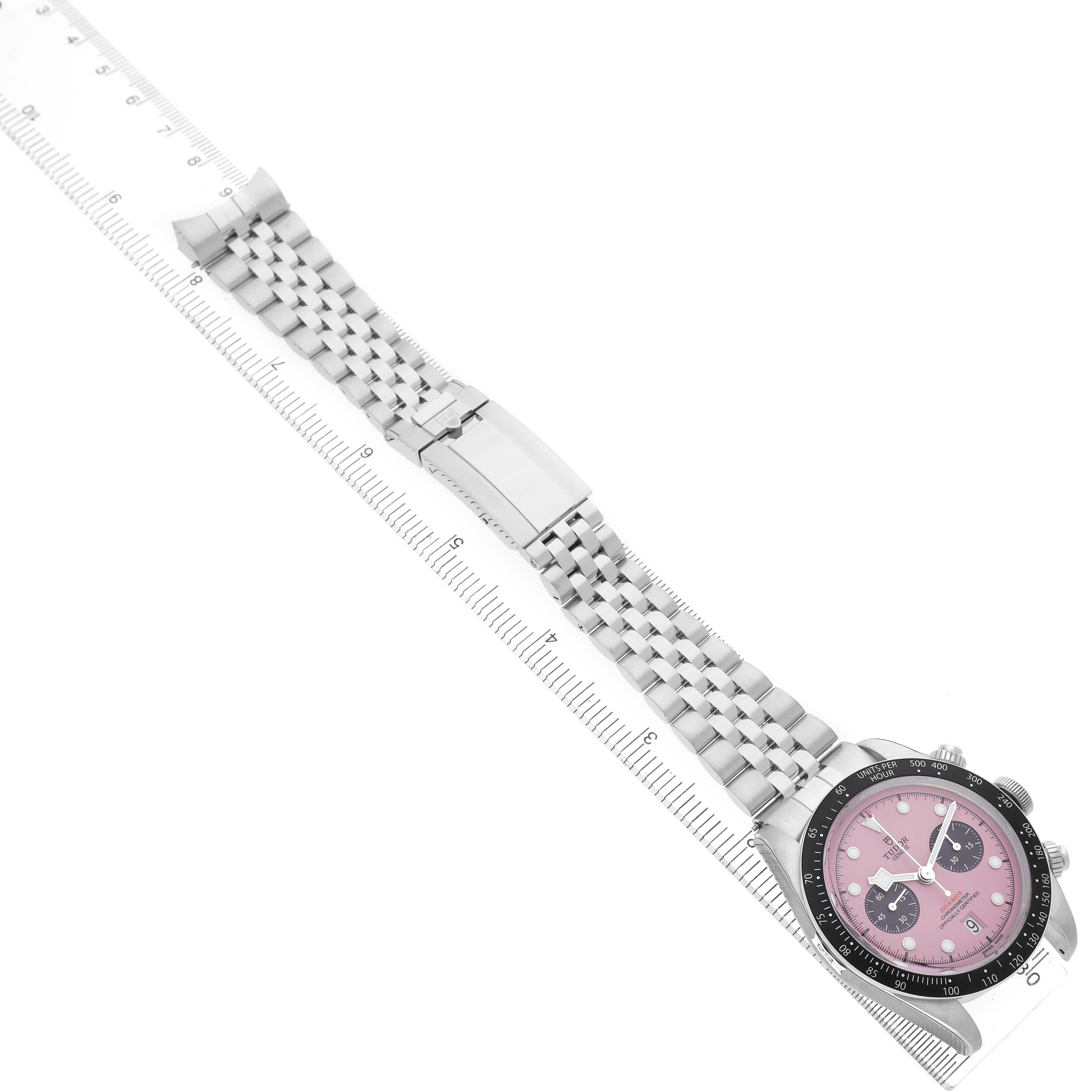 The Tudor Heritage Black Bay M79360N Men's Stainless Steel Pink Dial watch is shown at an angle highlighting the dial, bezel, bracelet, and clasp, with a ruler for size reference.